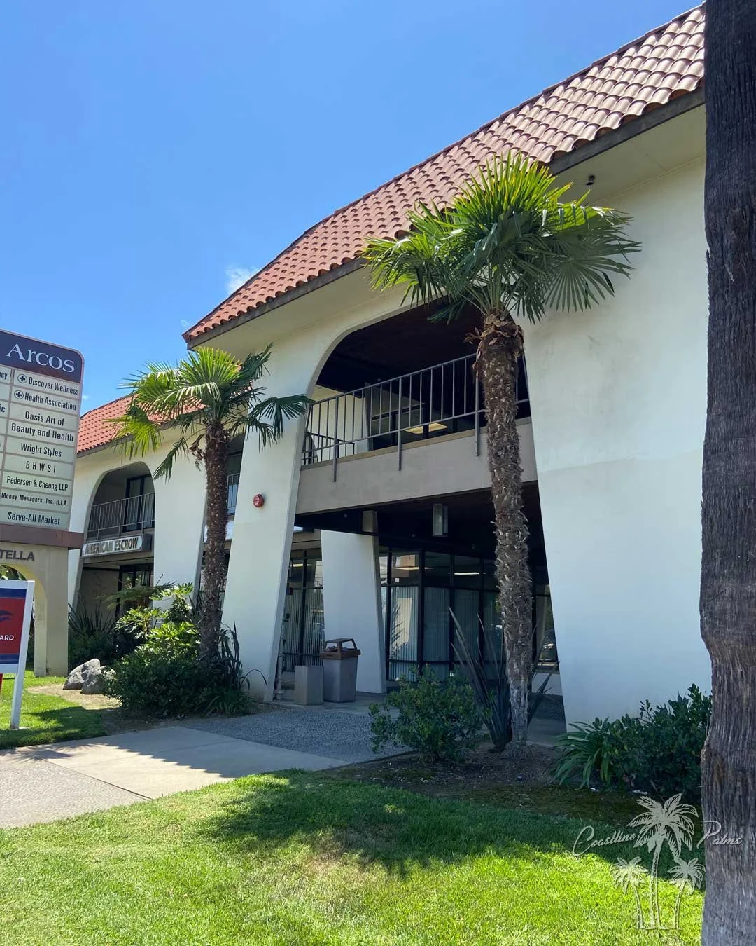 Windmill fan palms outside a commercial building with a red tile roof.
