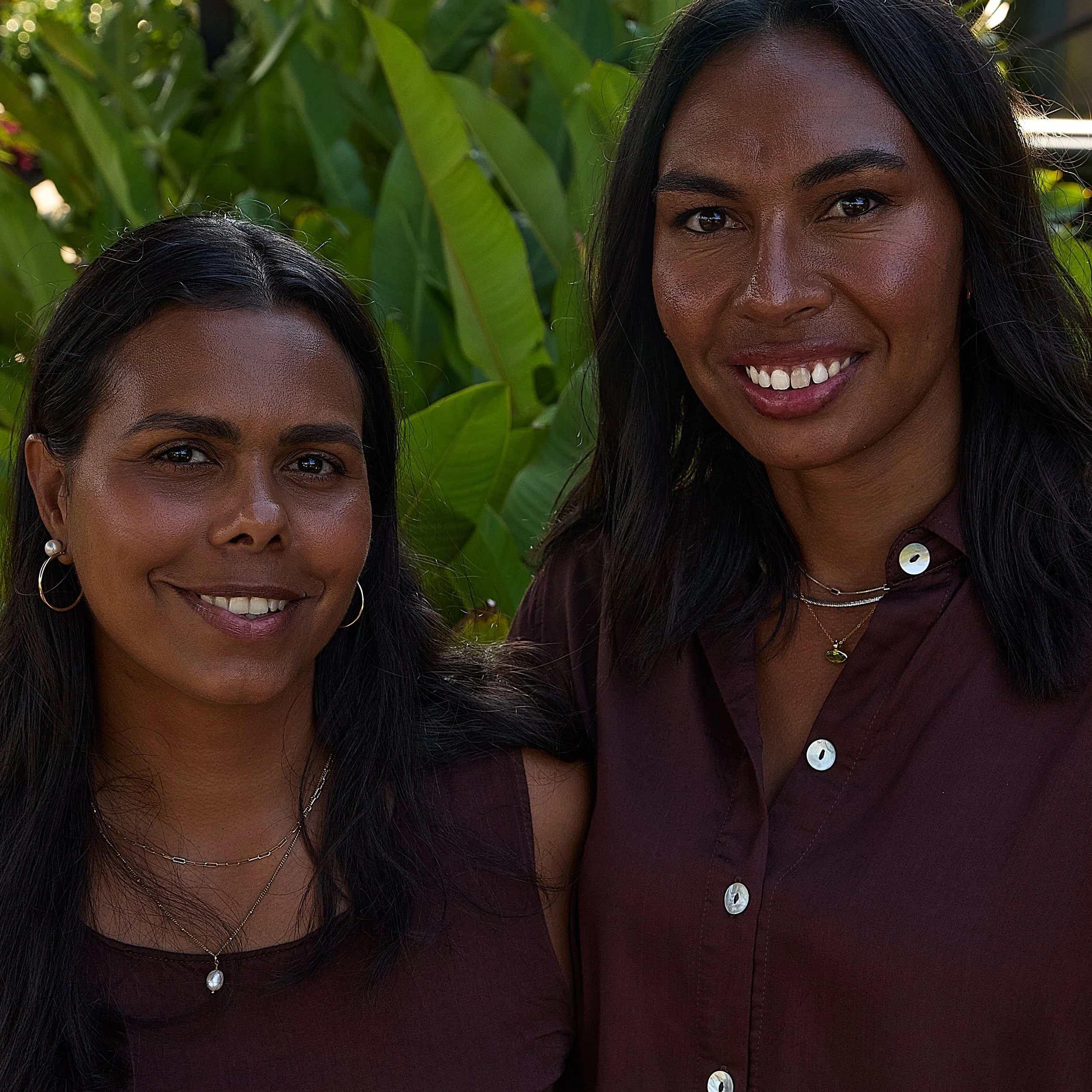 Close-up of ḺUNDU founders Elena Wangurra and Liandra Gaykamangu smiling together outdoors, with green foliage behind them.