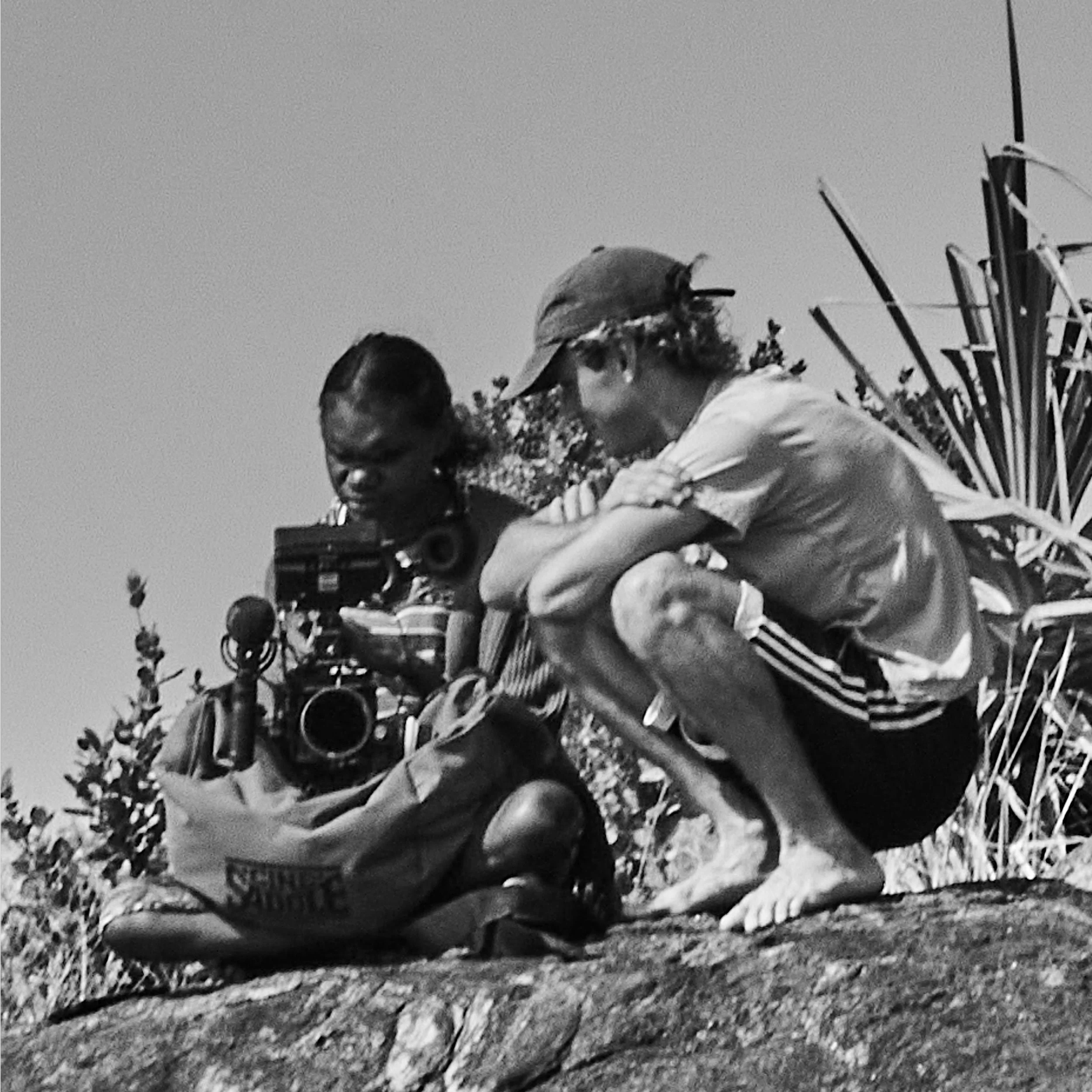Black-and-white photograph of Ed Triglione with a First Nations creative sitting together outdoors during a ḺUNDU project in East Arnhem Land.