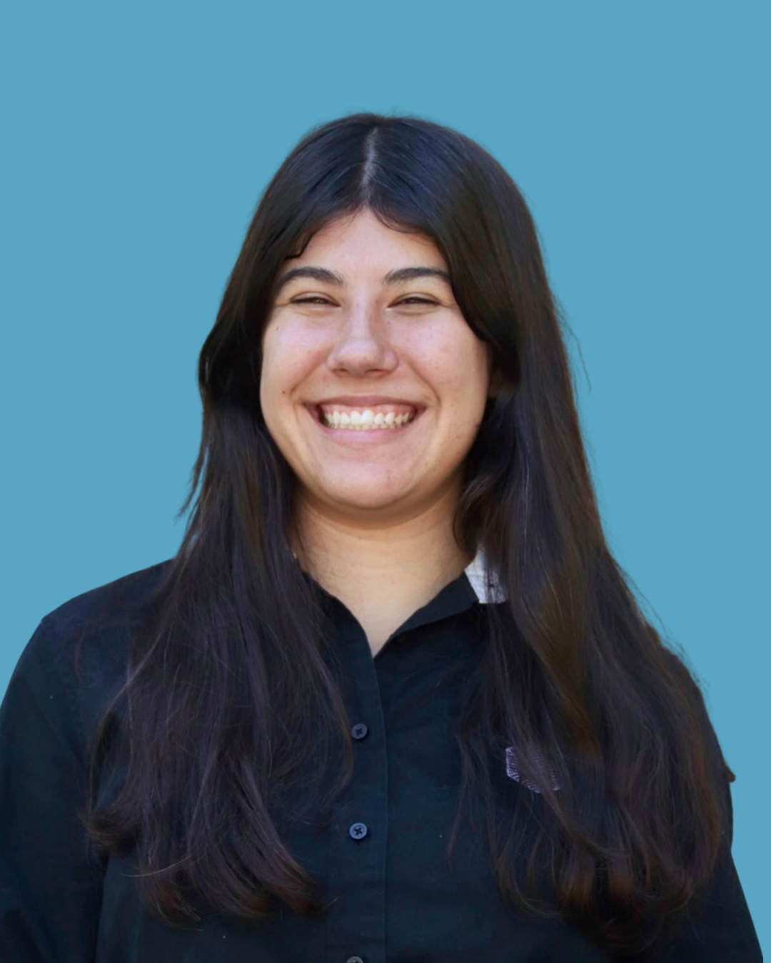 A young woman with long dark hair, smiling, wearing a black shirt, standing against a blue background.
