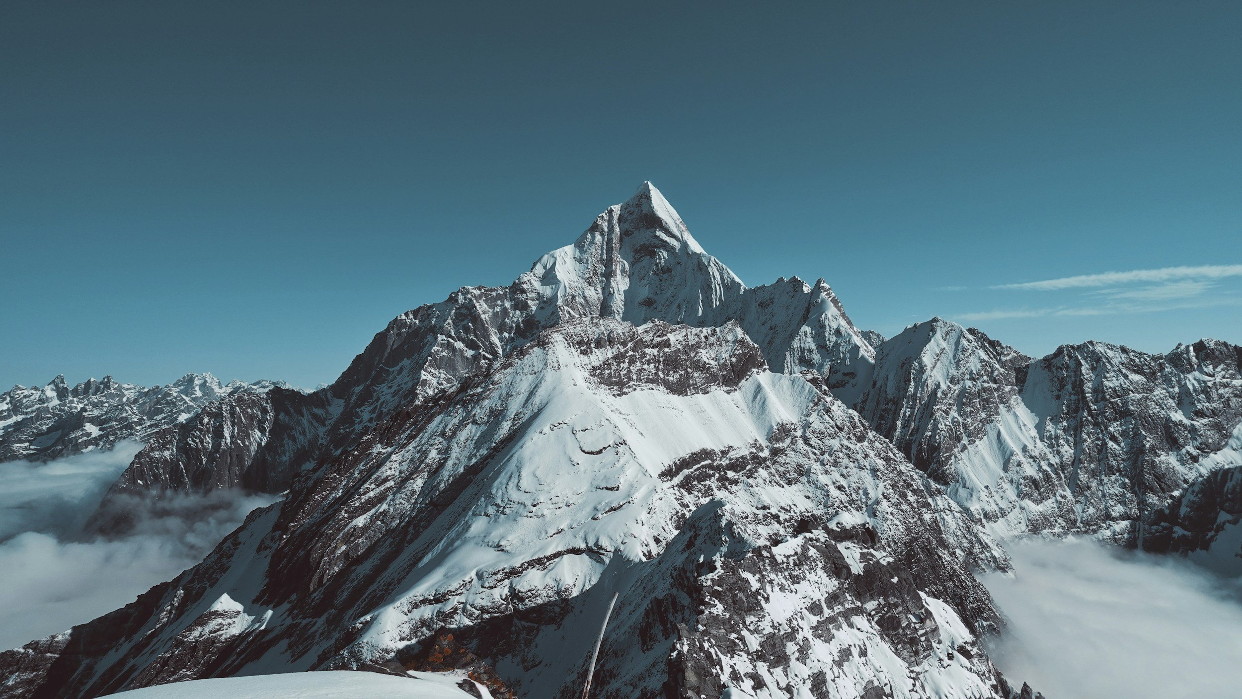 Dramatic snow-covered mountain peaks rising above clouds