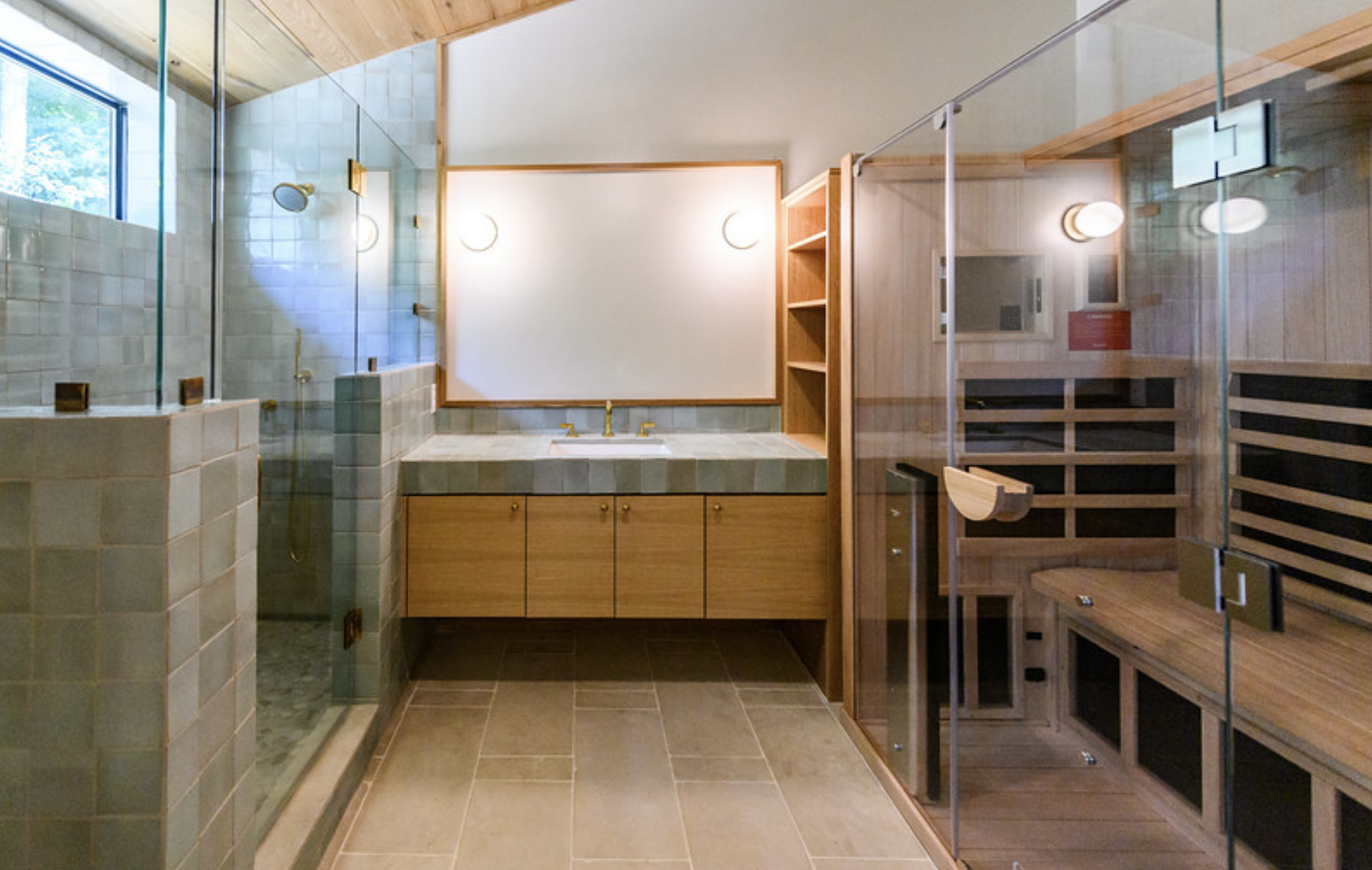 Interior of a modern bathroom with a walk-in shower, wooden cabinet with a sink, and a wooden sauna or hot room.