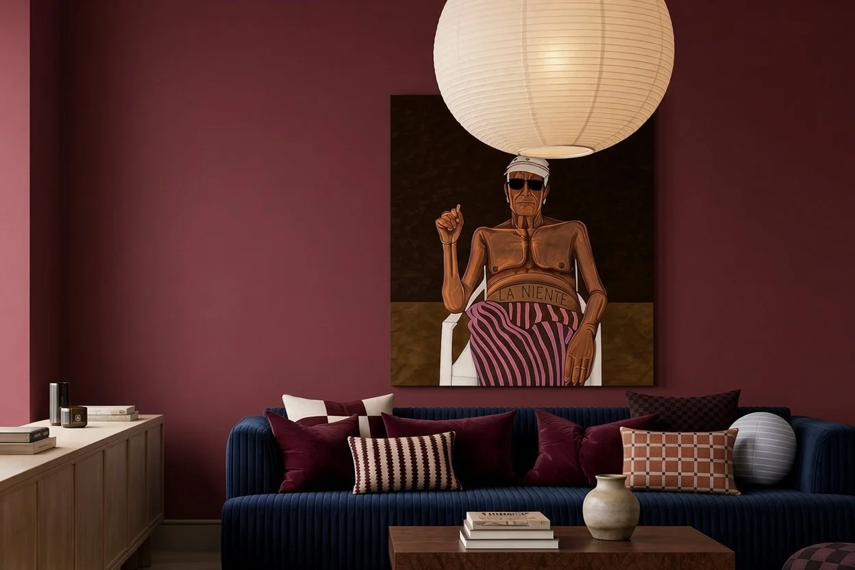 Living room with deep red walls, a navy velvet sofa piled with cushions, a paper lantern pendant and a large portrait artwork