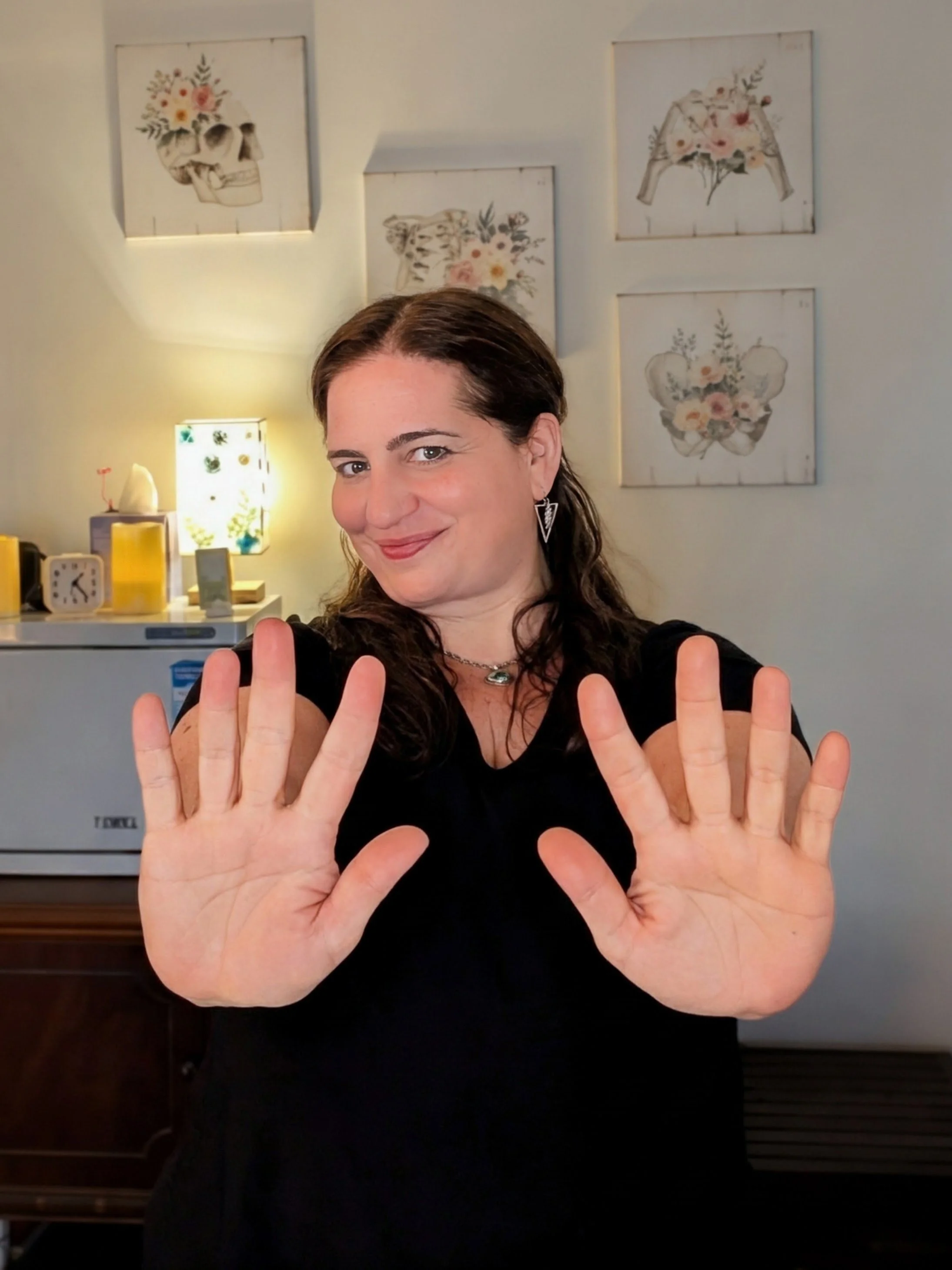 Rose Mollica Licensed Massage Therapist smiling in her studio with hands extended