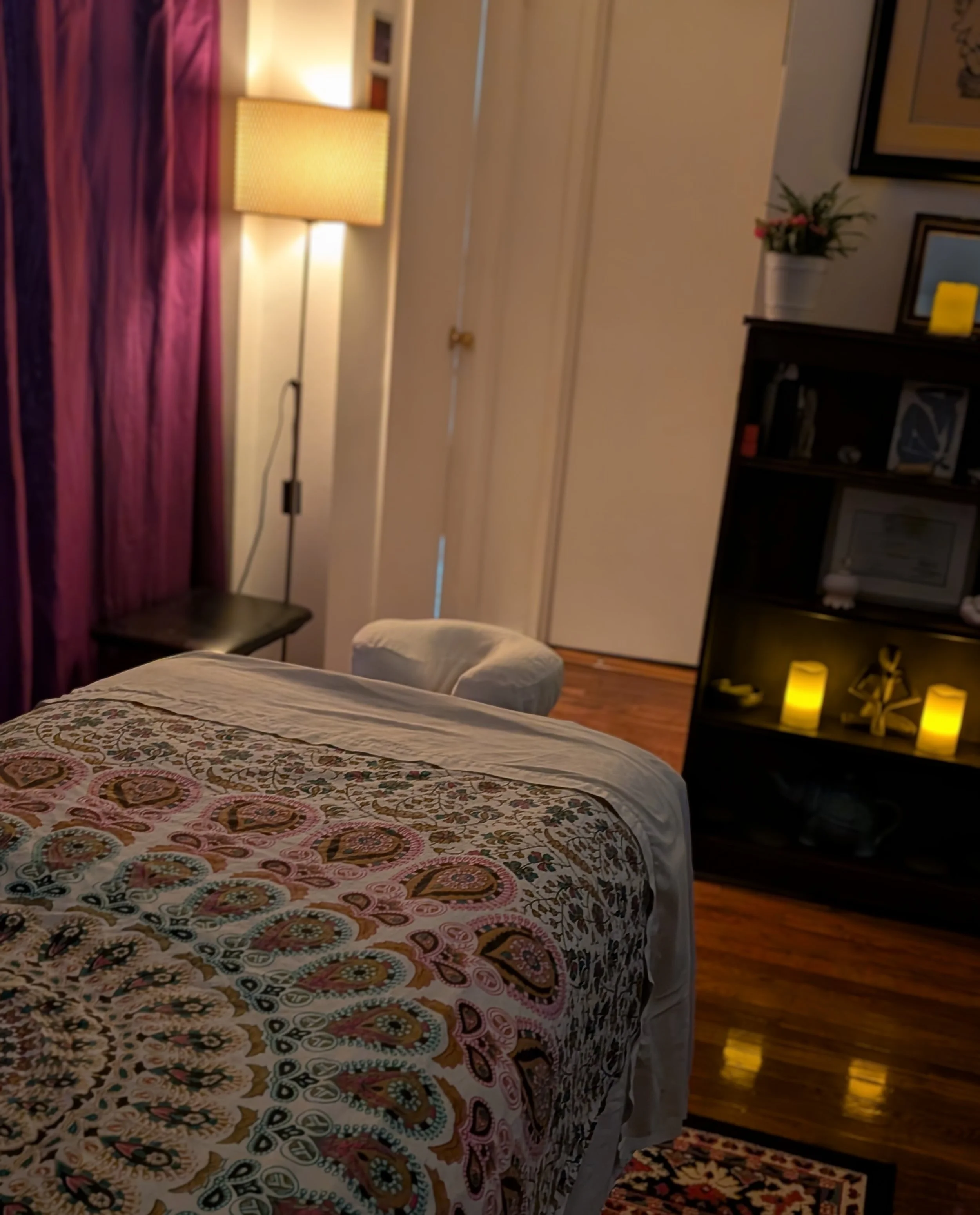 A cozy massage studio showing a relaxing massage table and warm ambient candle lighting.