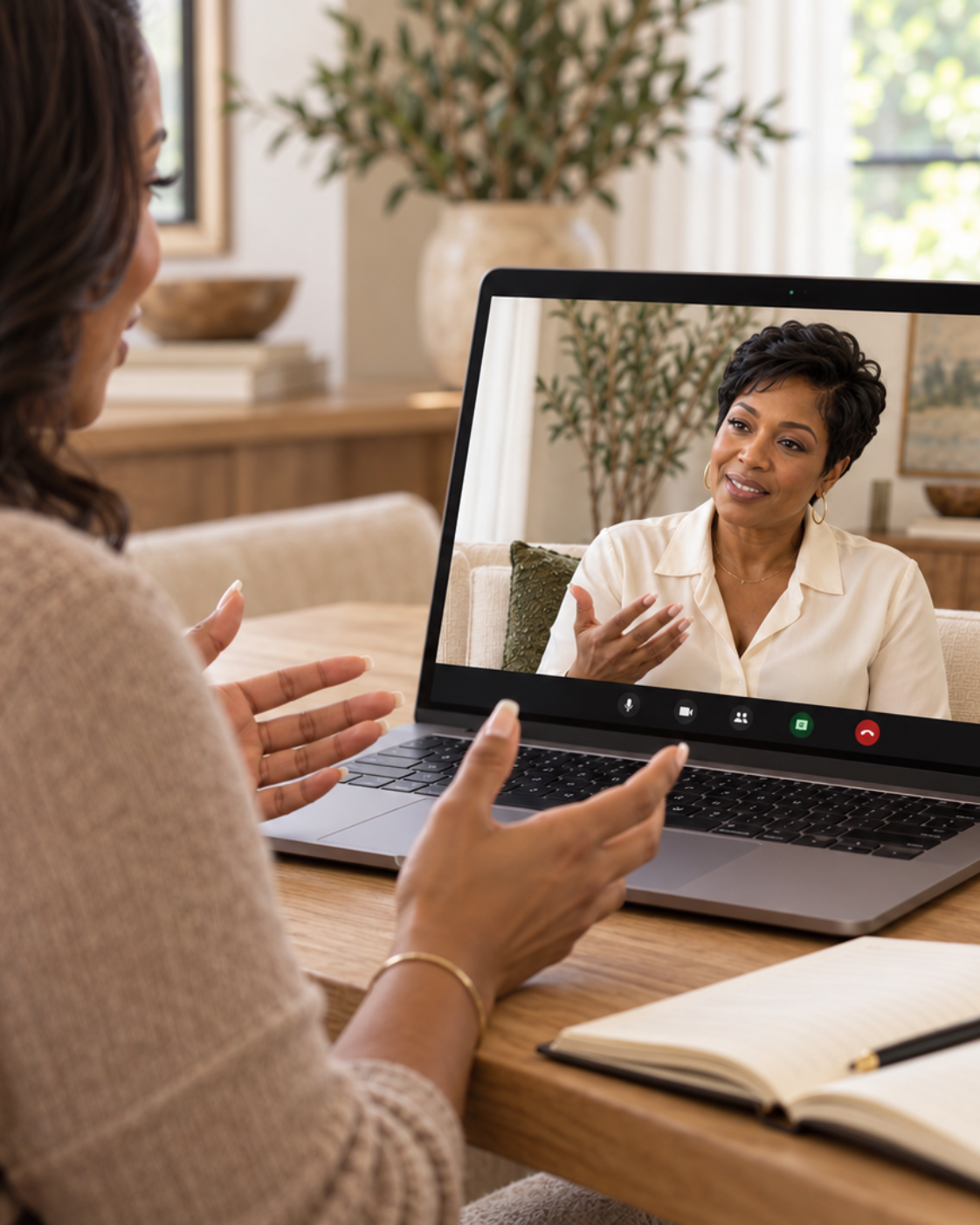 Woman on a video call talking to another woman on her laptop in a cozy, well-lit room with plants and home decor.