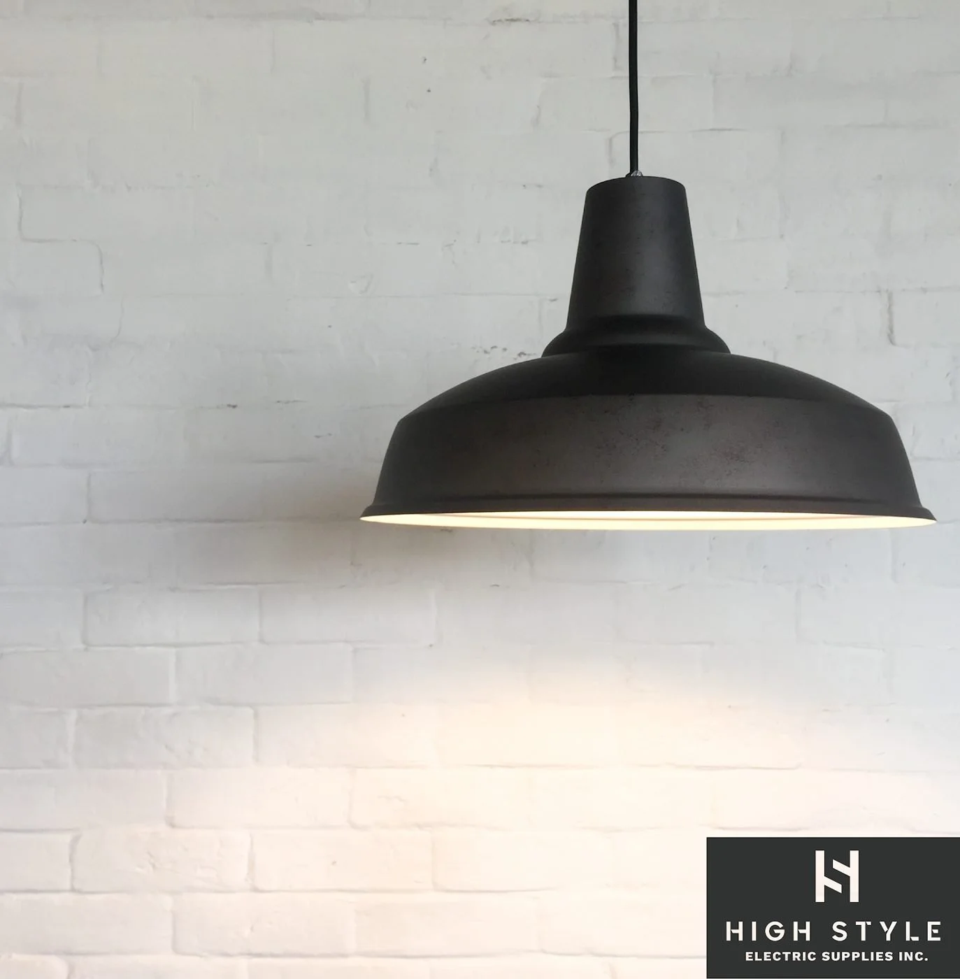Black pendant light against a white brick wall