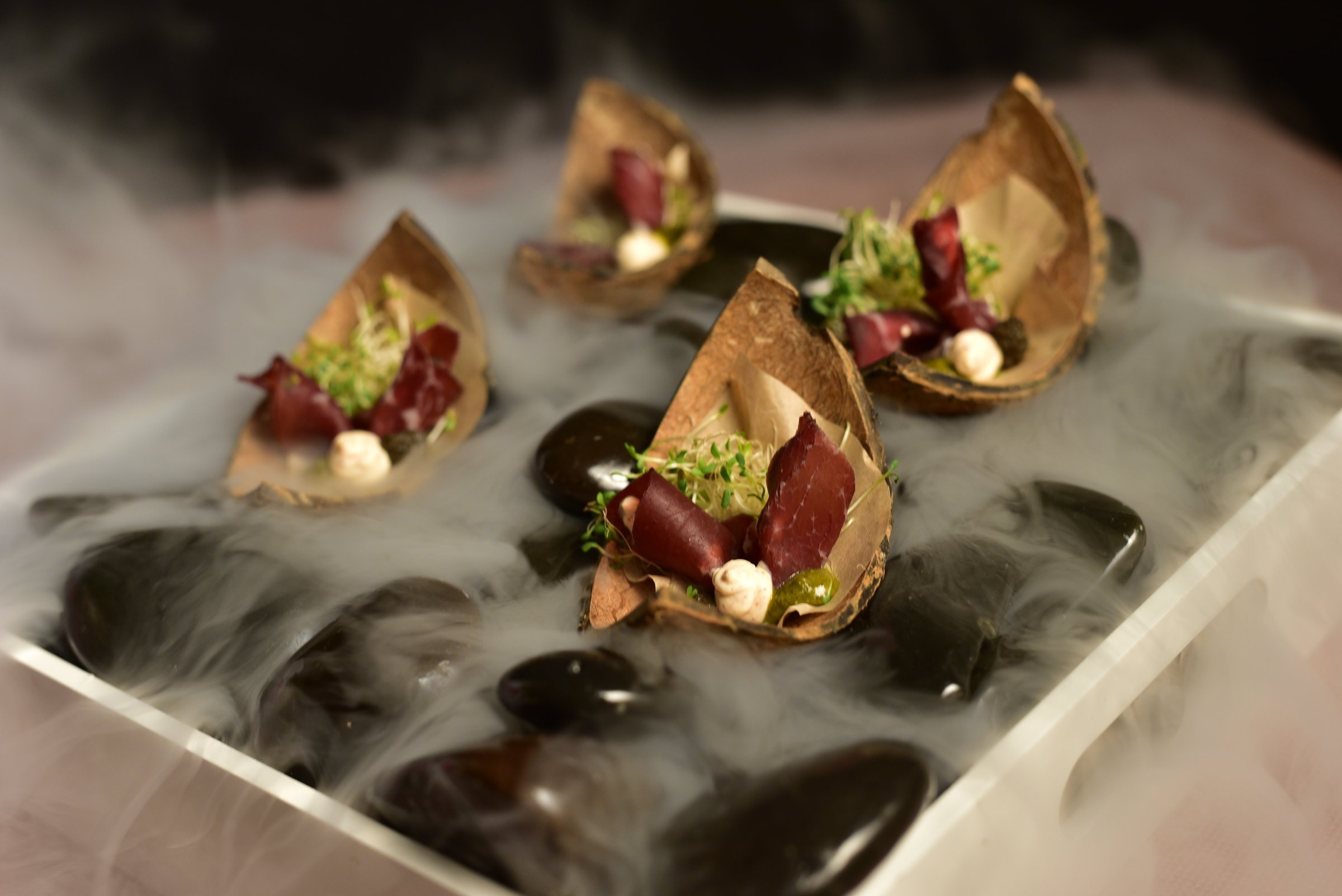 Canapés in crisp cones served on stones with dry ice smoke