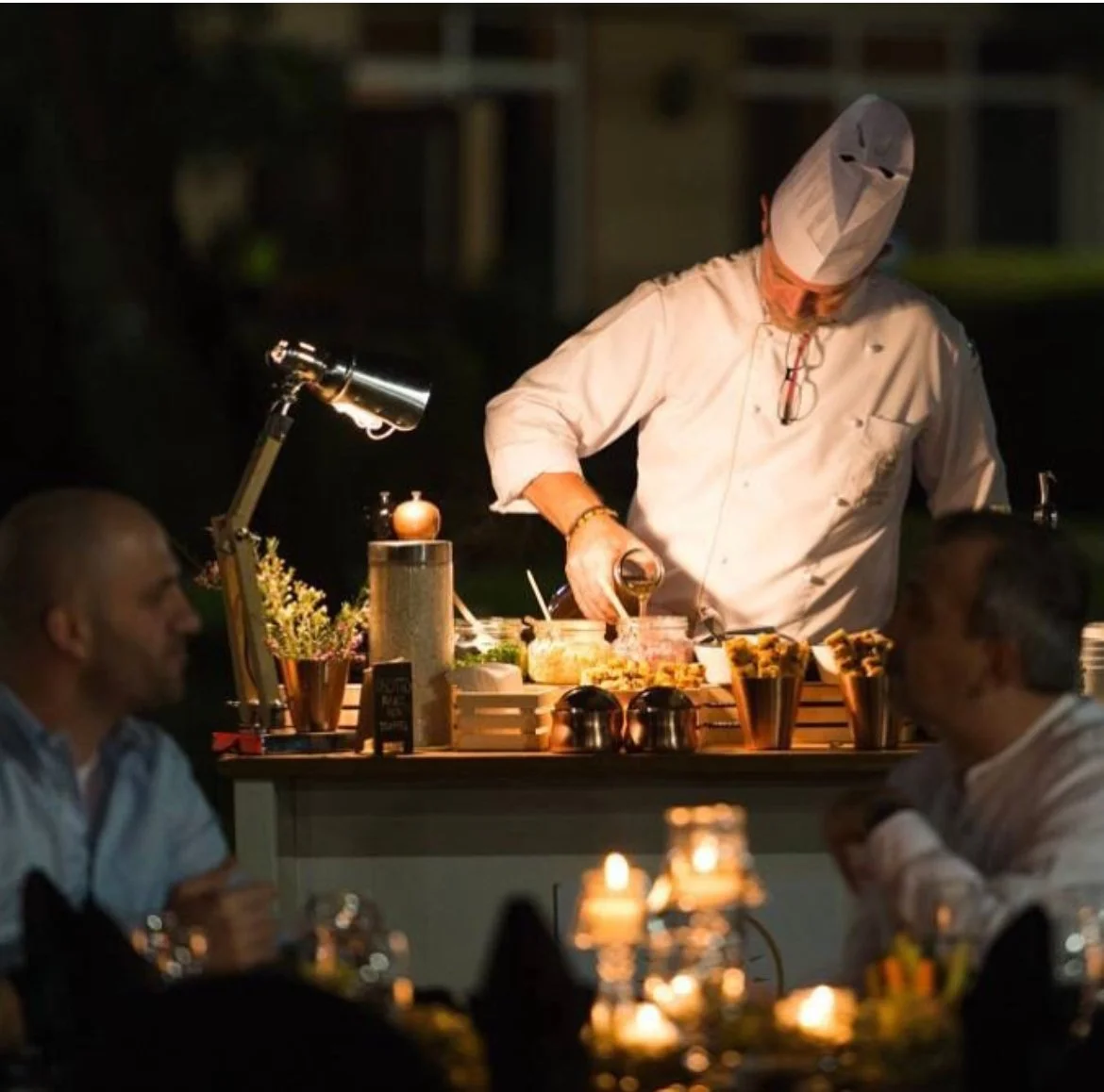 Chef carving at a candlelit live cooking station at night
