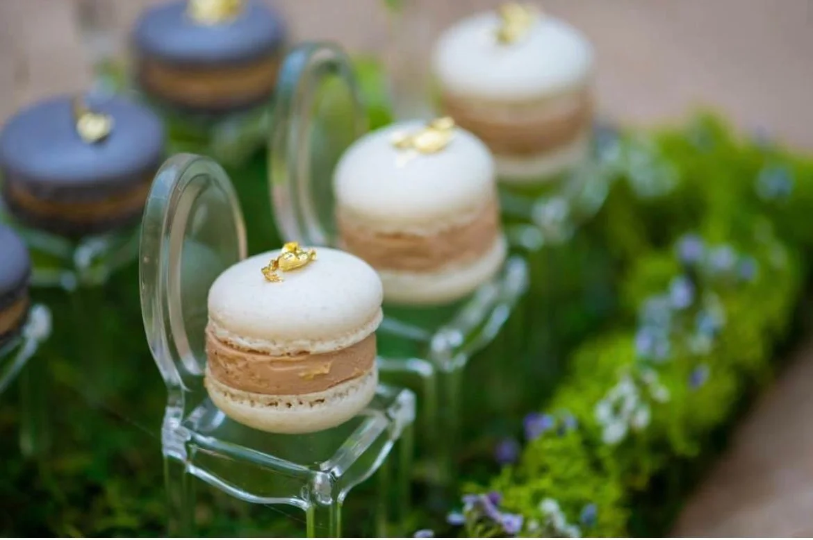 Macarons displayed on acrylic chairs over moss