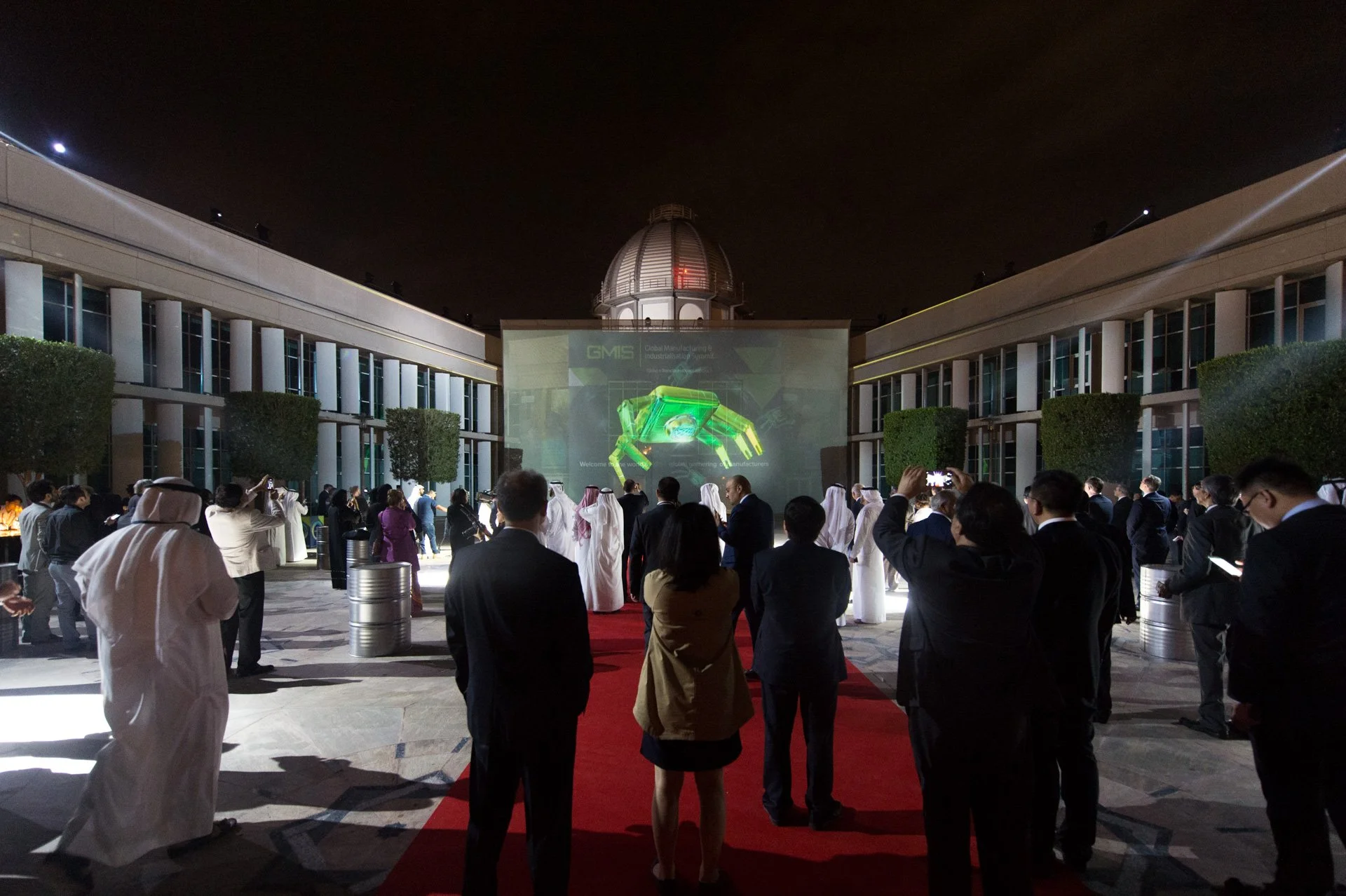Guests gathering on a red carpet in a floodlit courtyard