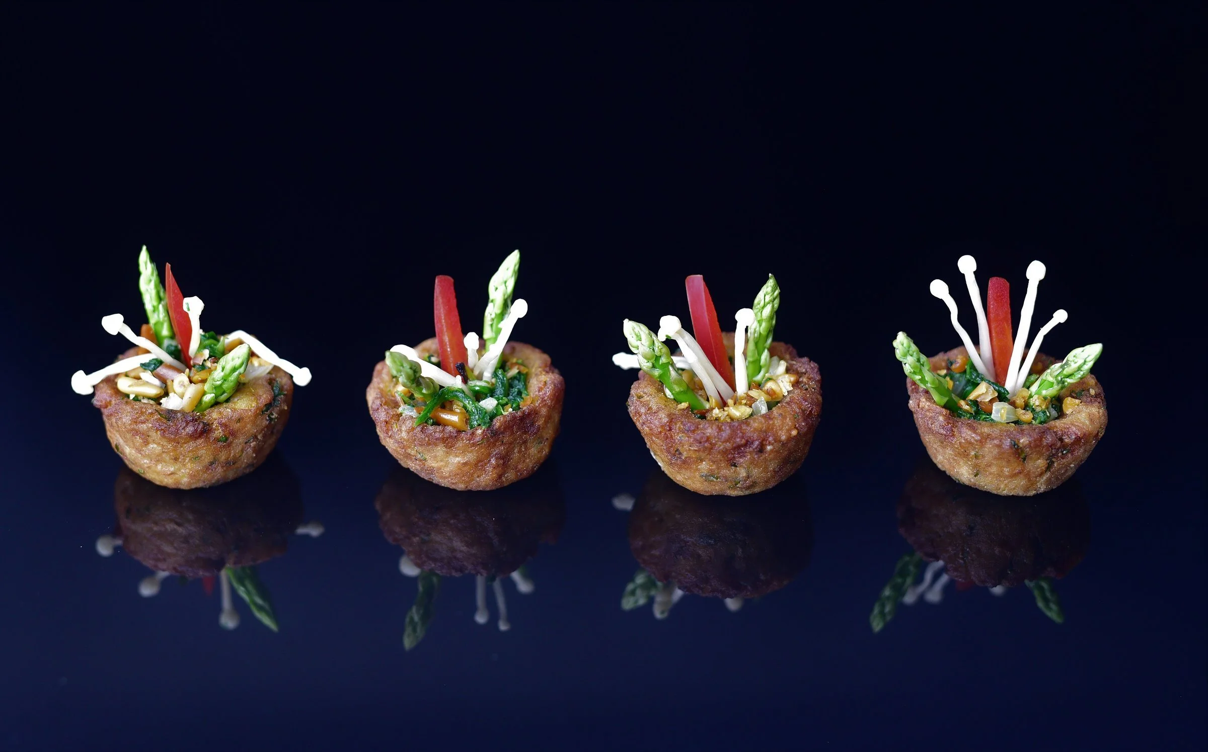 Four savoury tartlets topped with asparagus and enoki mushrooms