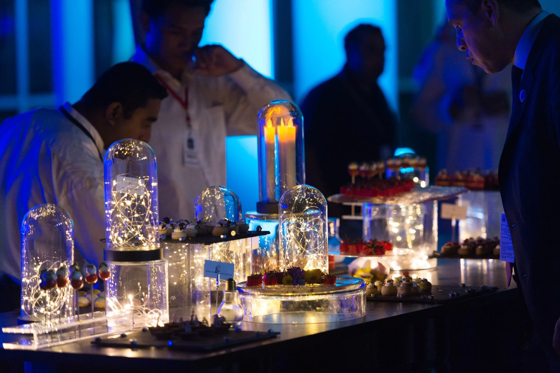 Chefs preparing canapés at a glowing glass cloche display
