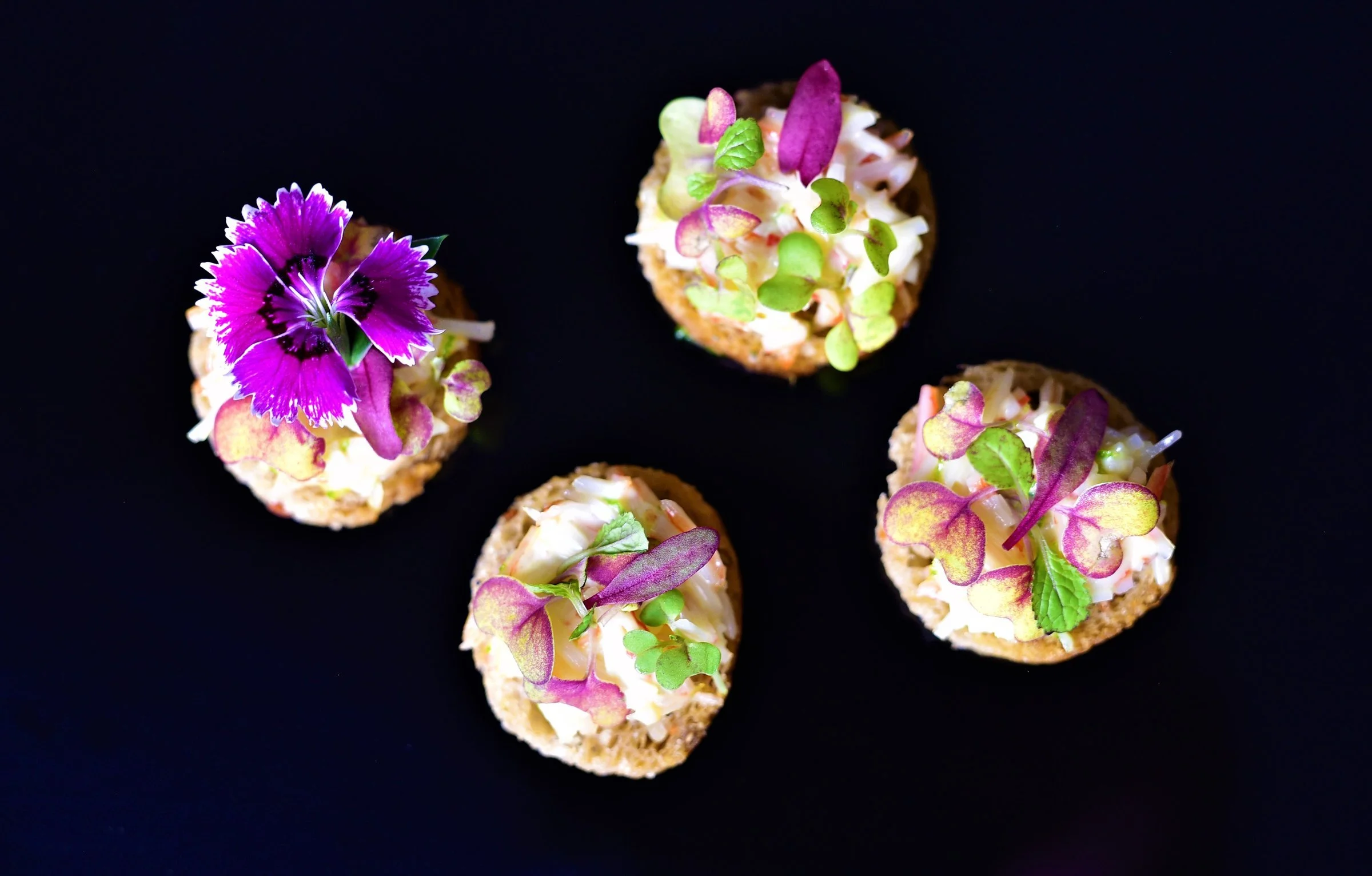 Four savoury canapés topped with edible purple flowers