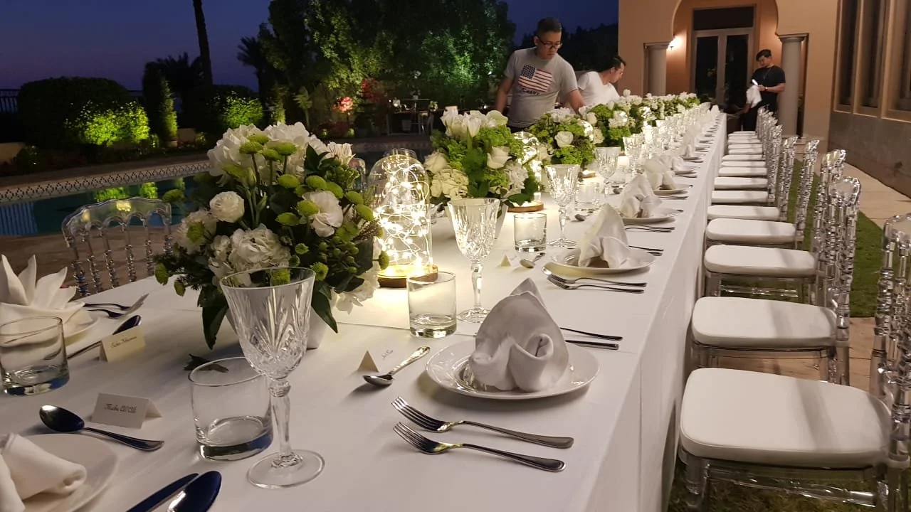 Long outdoor dinner table with white flowers at dusk