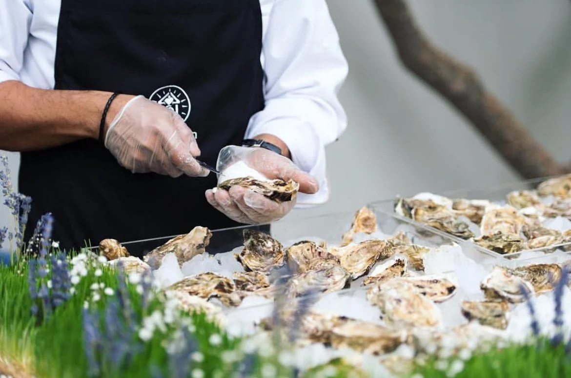 Chef in gloves opening fresh oysters at a seafood station