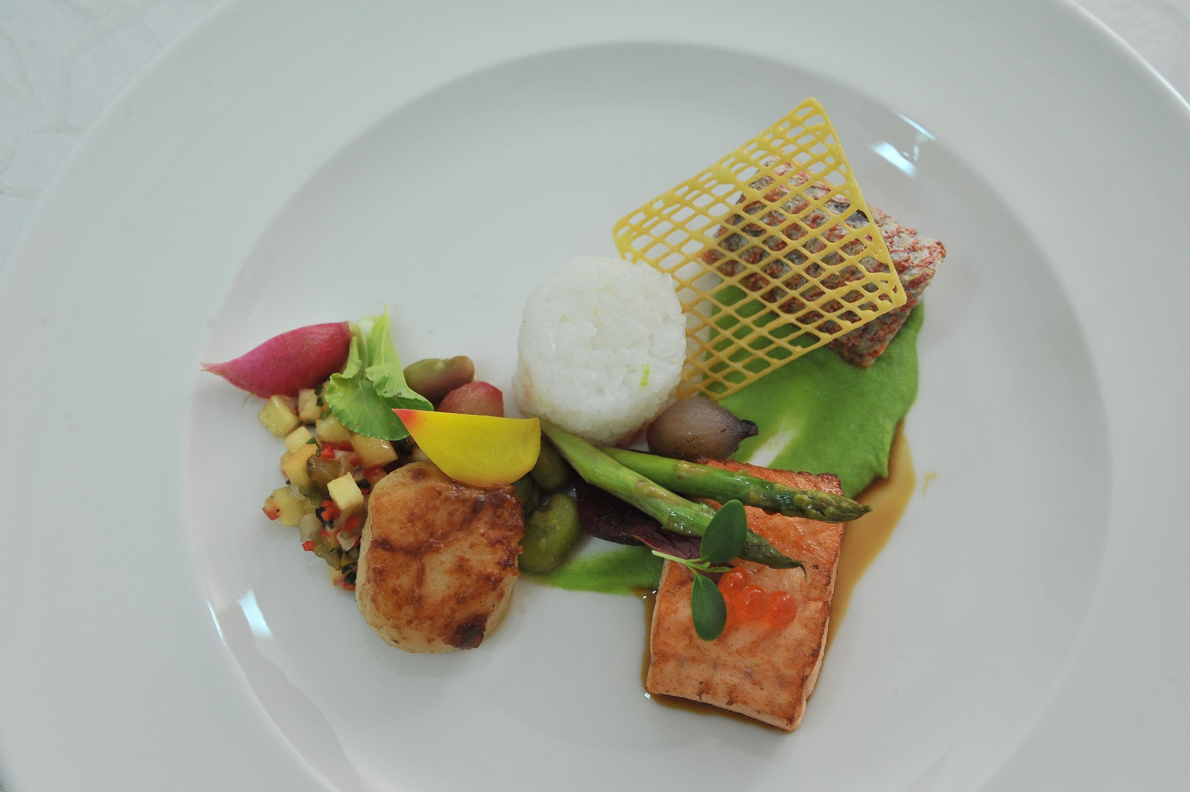 Pan-seared salmon with vegetables and crisp on a white plate