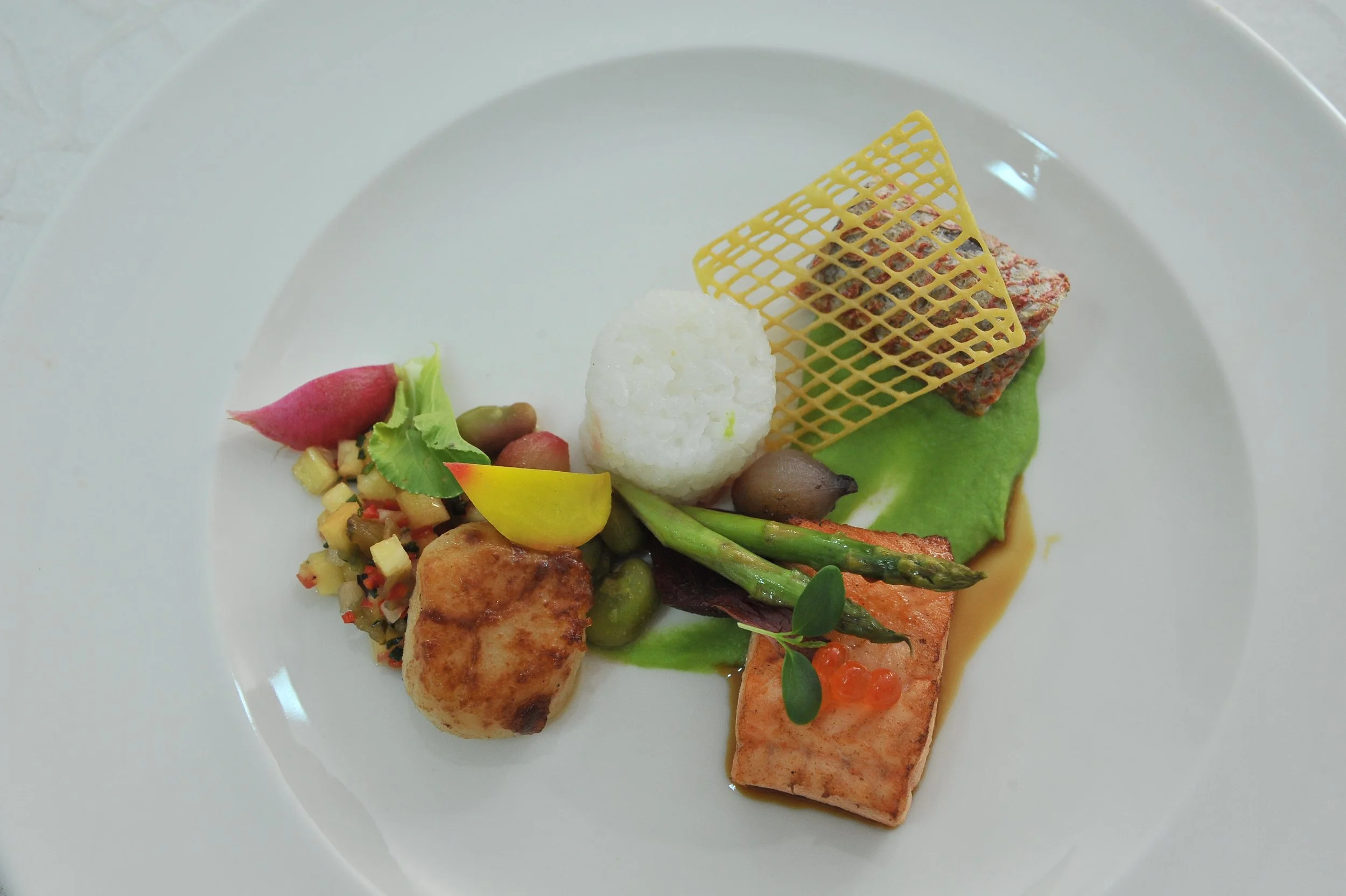 Pan-seared salmon with vegetables and crisp on a white plate