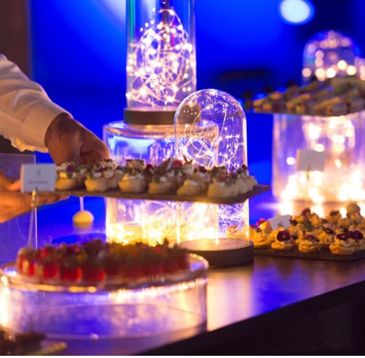 Guest helping themselves to desserts at a blue-lit display