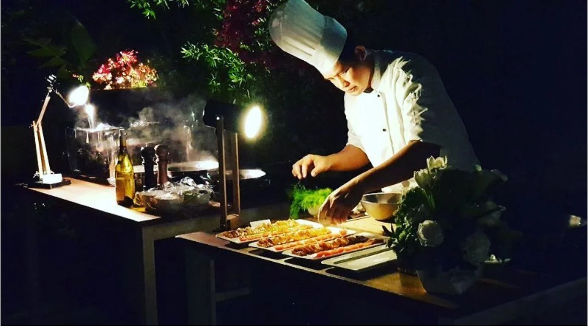 Chef cooking at a candlelit live station at night