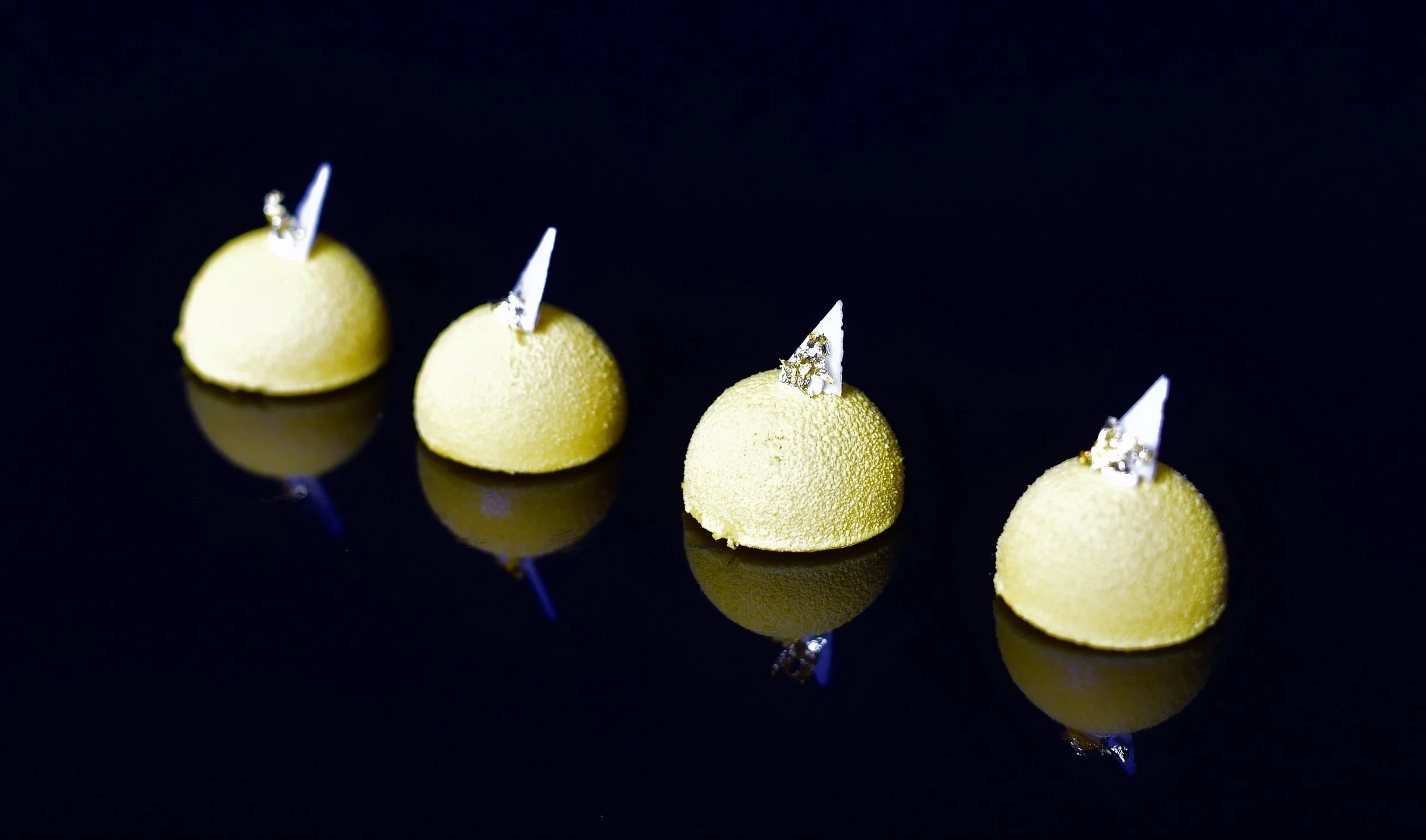 Four pale green dome canapés with edible silver leaf