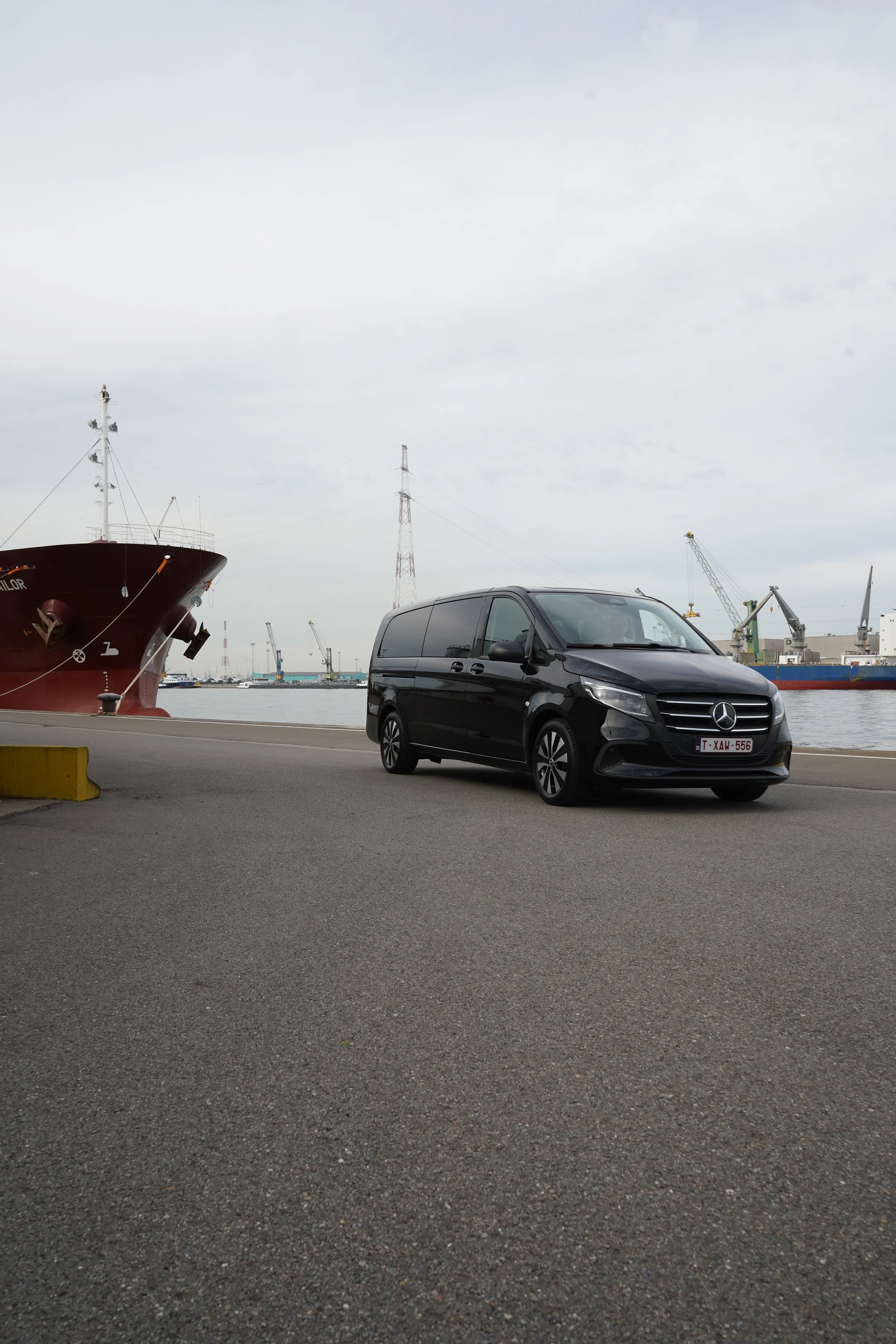 Zwarte Mercedes-bestelwagen van GDS Trans Service in een industriële haven, met vrachtschip, kranen en elektriciteitsmast op de achtergrond.
