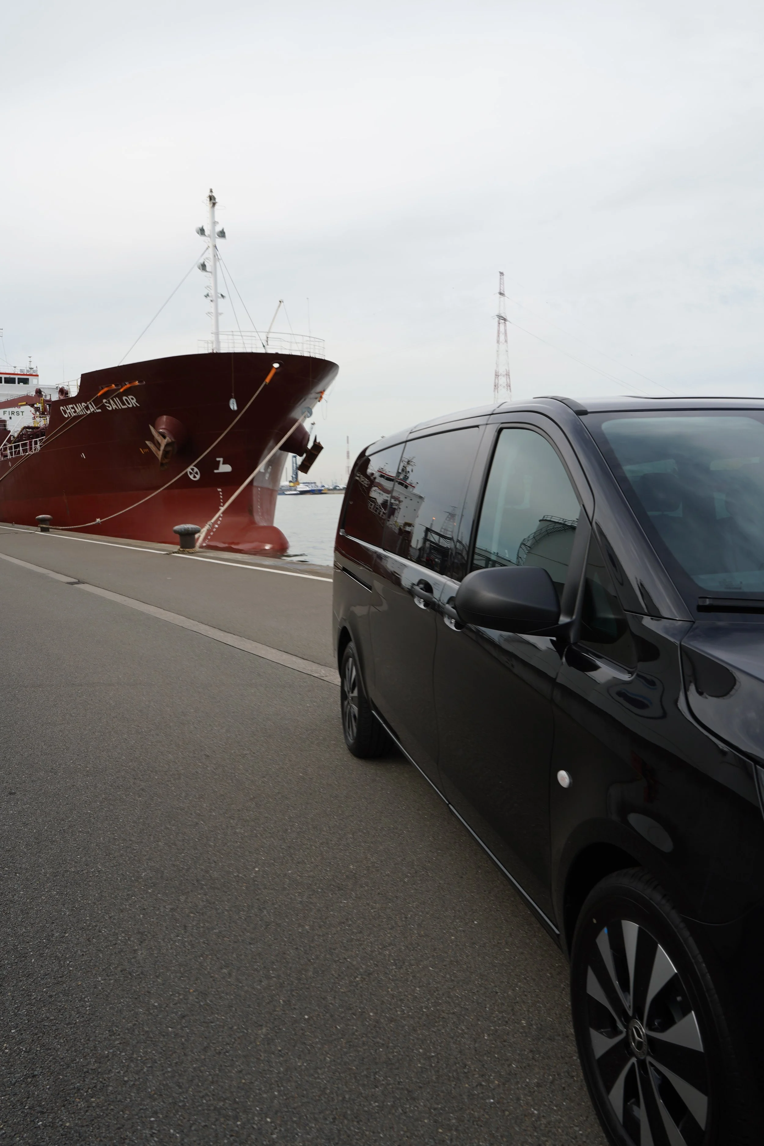 GDS Trans Service Rode vrachtschip naast een zwarte auto in een haven.