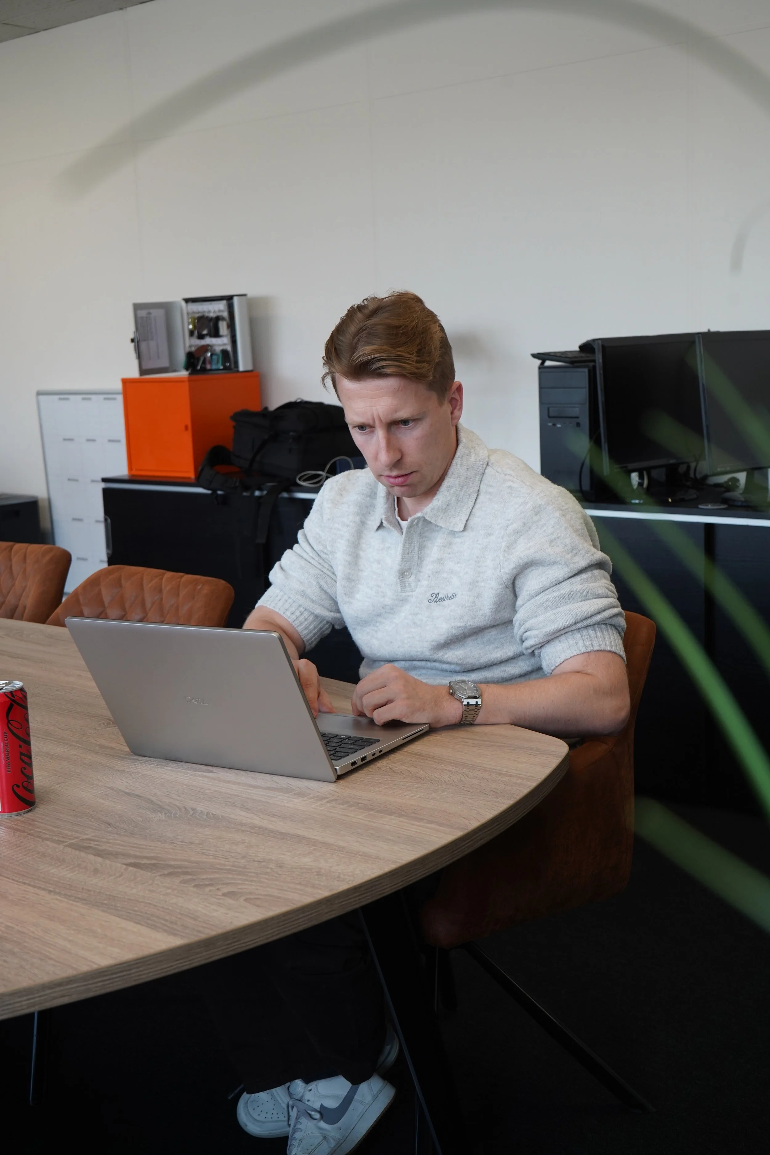 Andy van GDS Trans Service werkt op een laptop aan een houten tafel in een kantoorruimte.