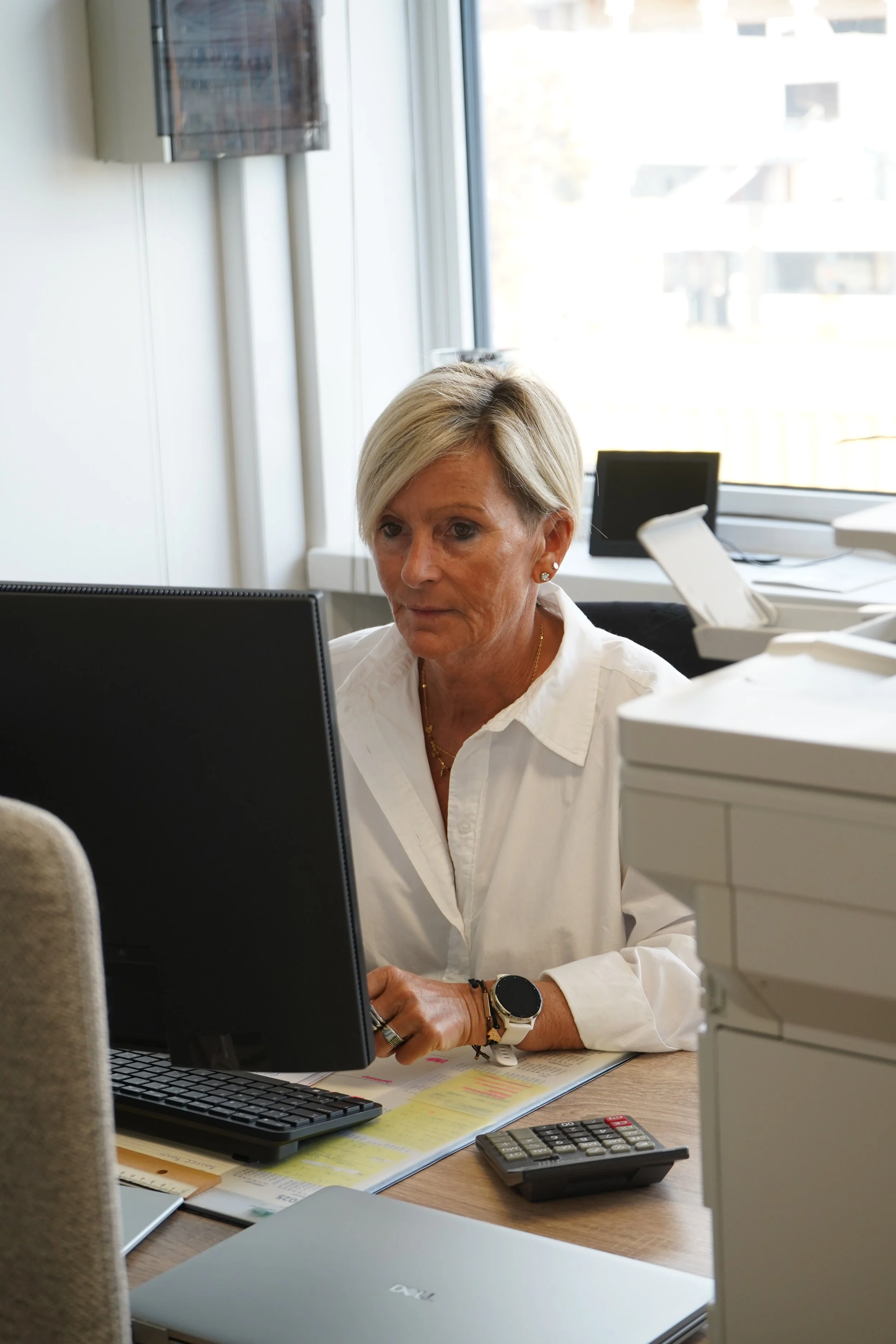 Collega GDS Trans Service werkt aan een bureau met laptop, documenten en rekenmachine.