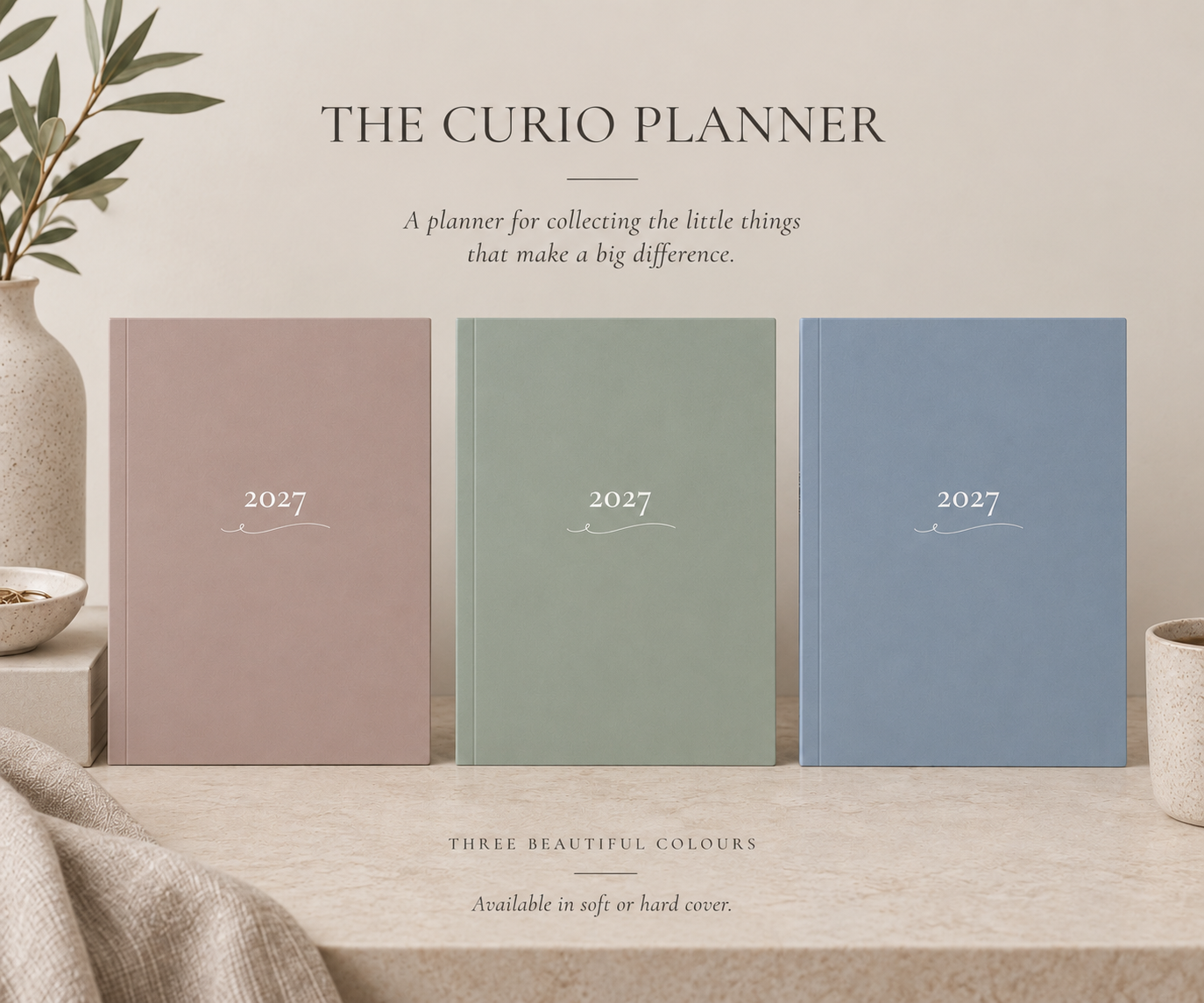 The image features three 2027 planners in soft pastel colors—pink, green, and blue—standing side by side on a beige surface, with a beige and green background. The text above reads, "The Curio Planner," with a description about collecting little things that make a big difference, and mentions availability in soft or hard cover.