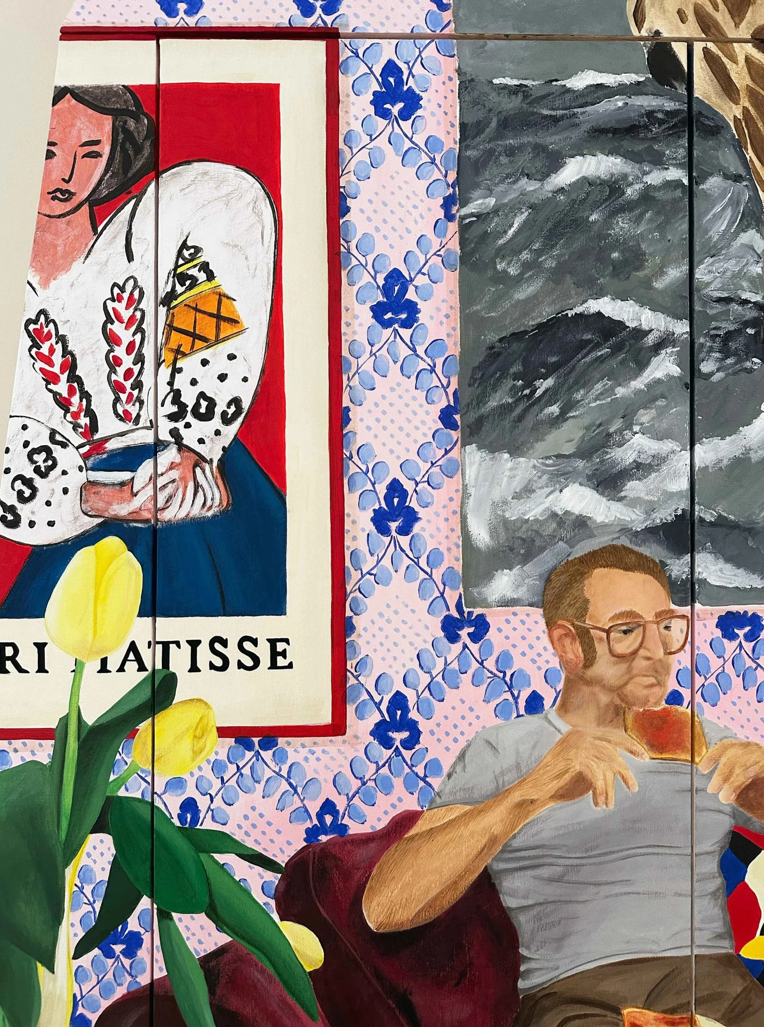 Une fresque murale représentant une femme avec un serpent, des fleurs jaunes en premier plan, une mer agitée en arrière-plan, des motifs floraux bleus et un homme en train de manger une pizza.