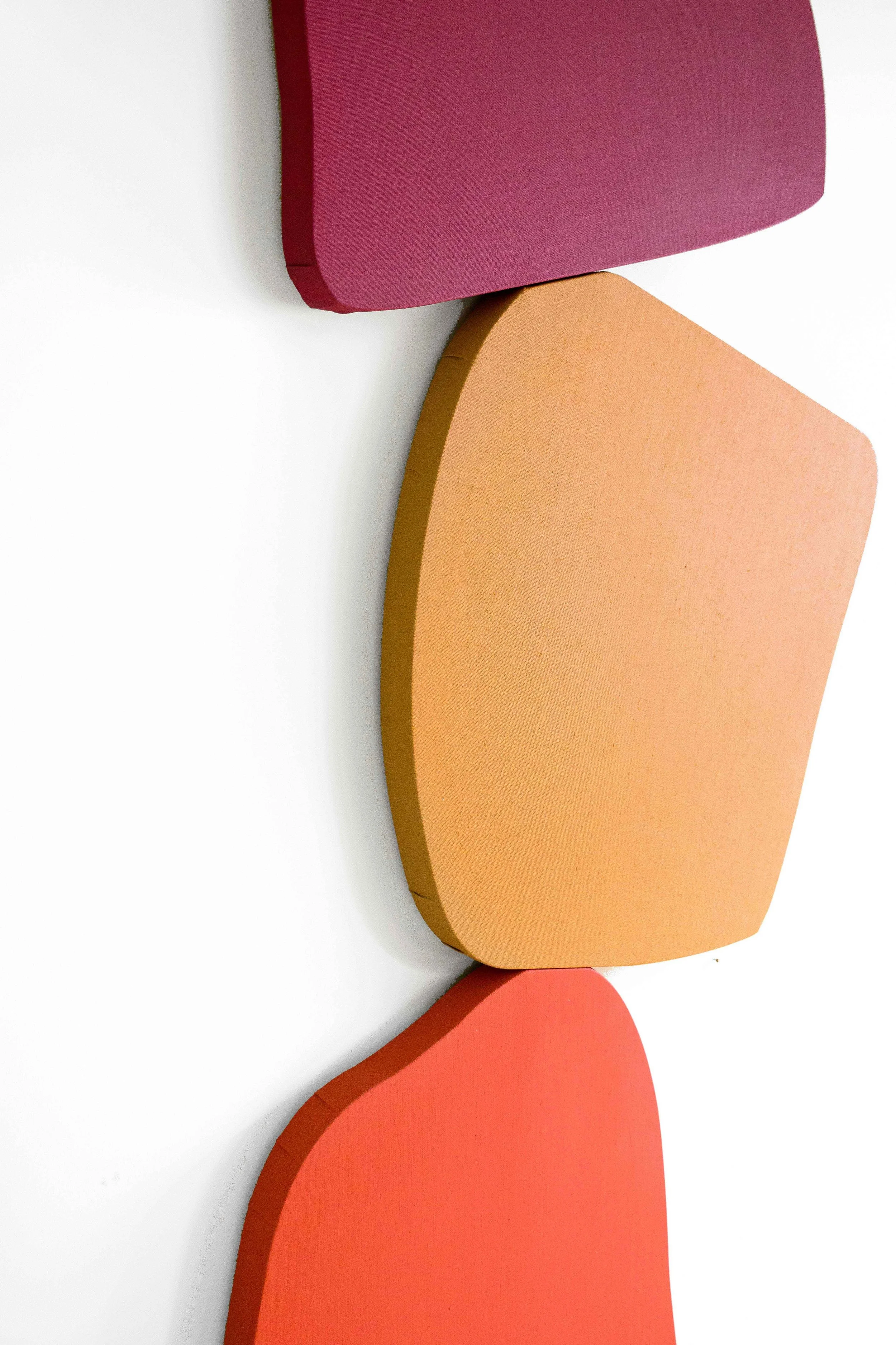Close up. Formes colorées et châssis de forme assemblés pour créer une sculpture murale. Rouge vin, ocre et orange. 