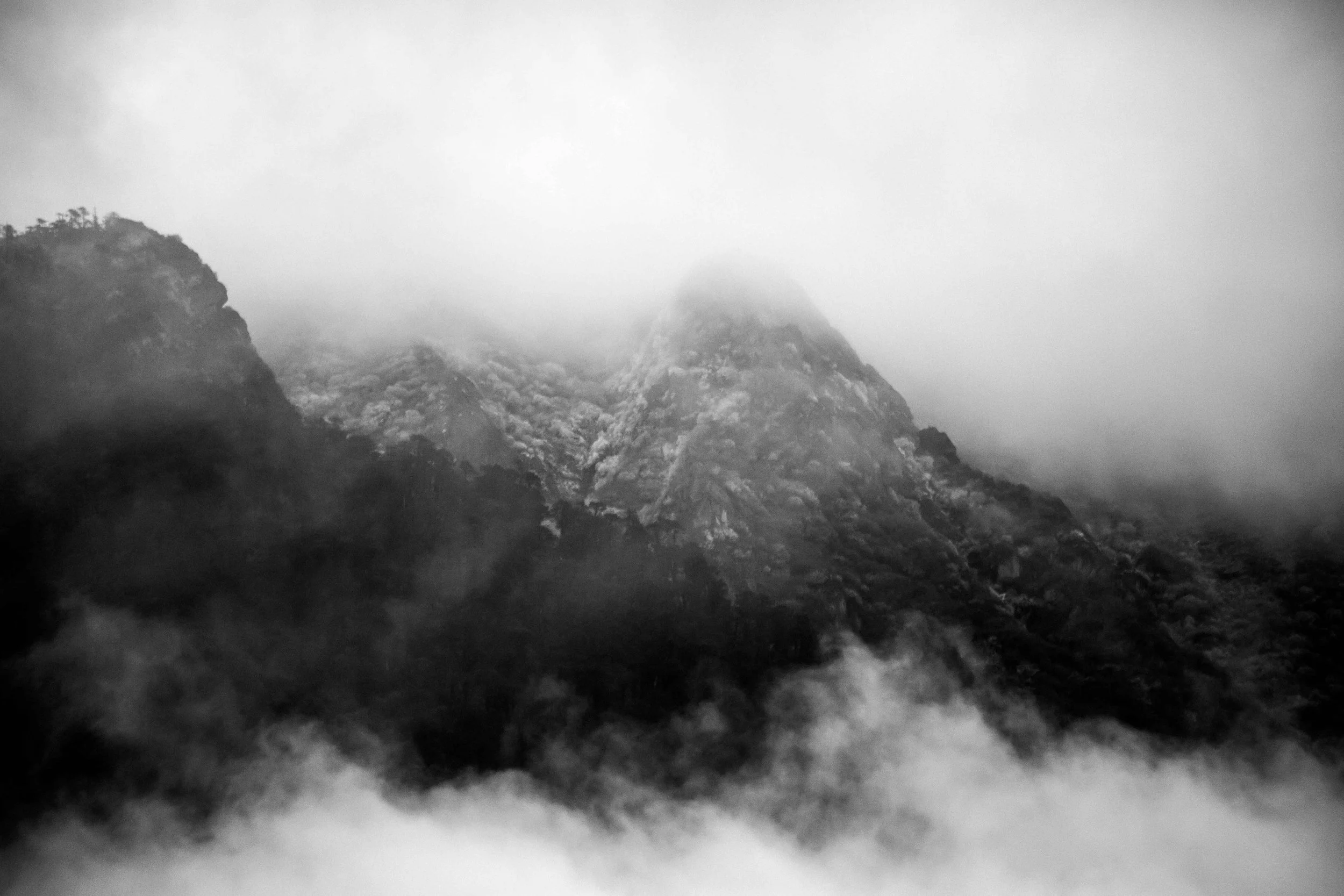 Montagnes brumeuses enneigées ou rocheuses dans un paysage nuageux en noir et blanc. Everest