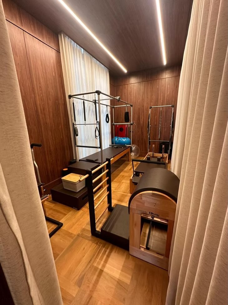 Sala de fisioterapia com equipamento de pilates, barras e bolas de exercícios