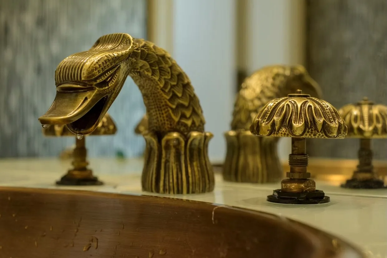 Luminárias decorativas em formato de cabeças de cobra feitas de material dourado com detalhes em relevo.