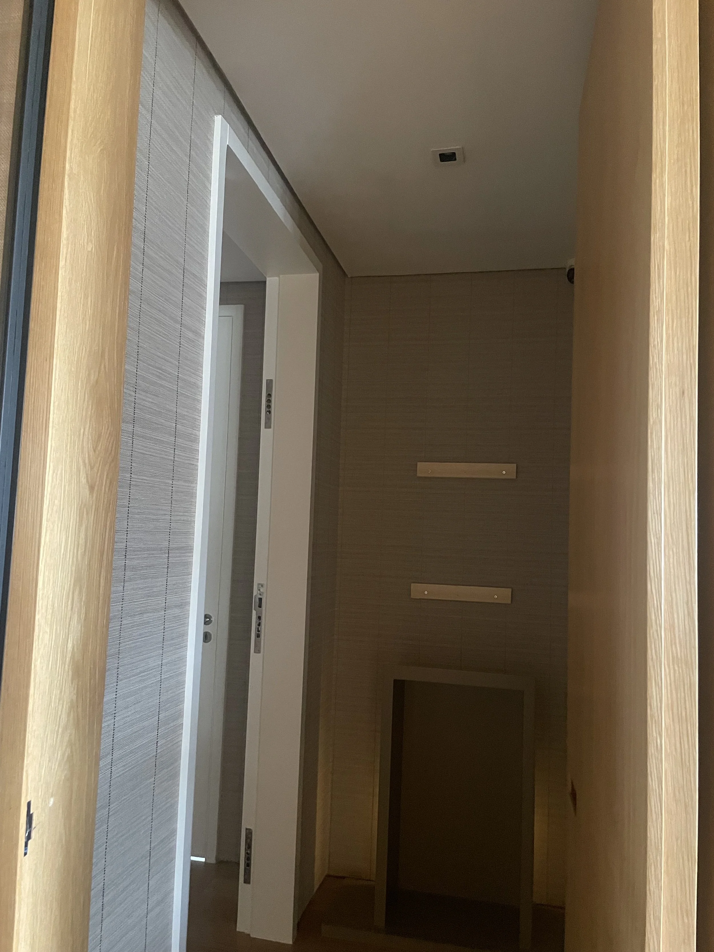 Elevador em construção, com portas abertas, paredes de cerca de madeira e uma sala vazia