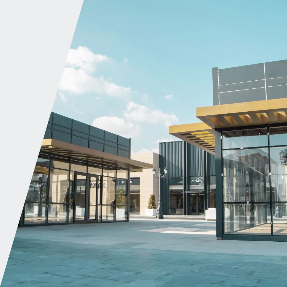 Empty modern outdoor shopping center with glass storefronts and a blue sky