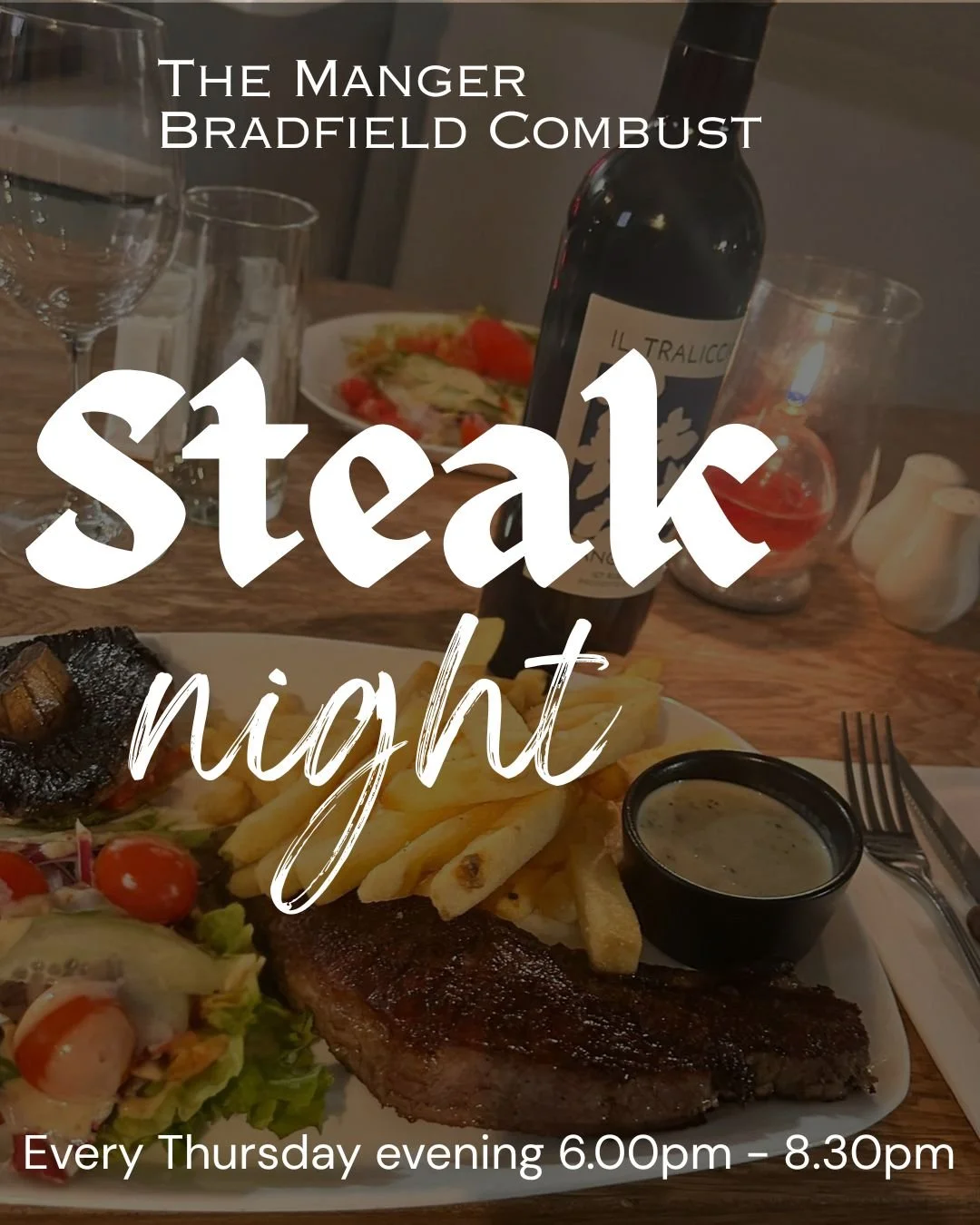 A plate with steak, French fries, a small container of green sauce, and salad with cherry tomatoes. A glass bottle of red wine, wine glasses, and a carafe are on the wooden table in the background, along with some salt and pepper shakers.