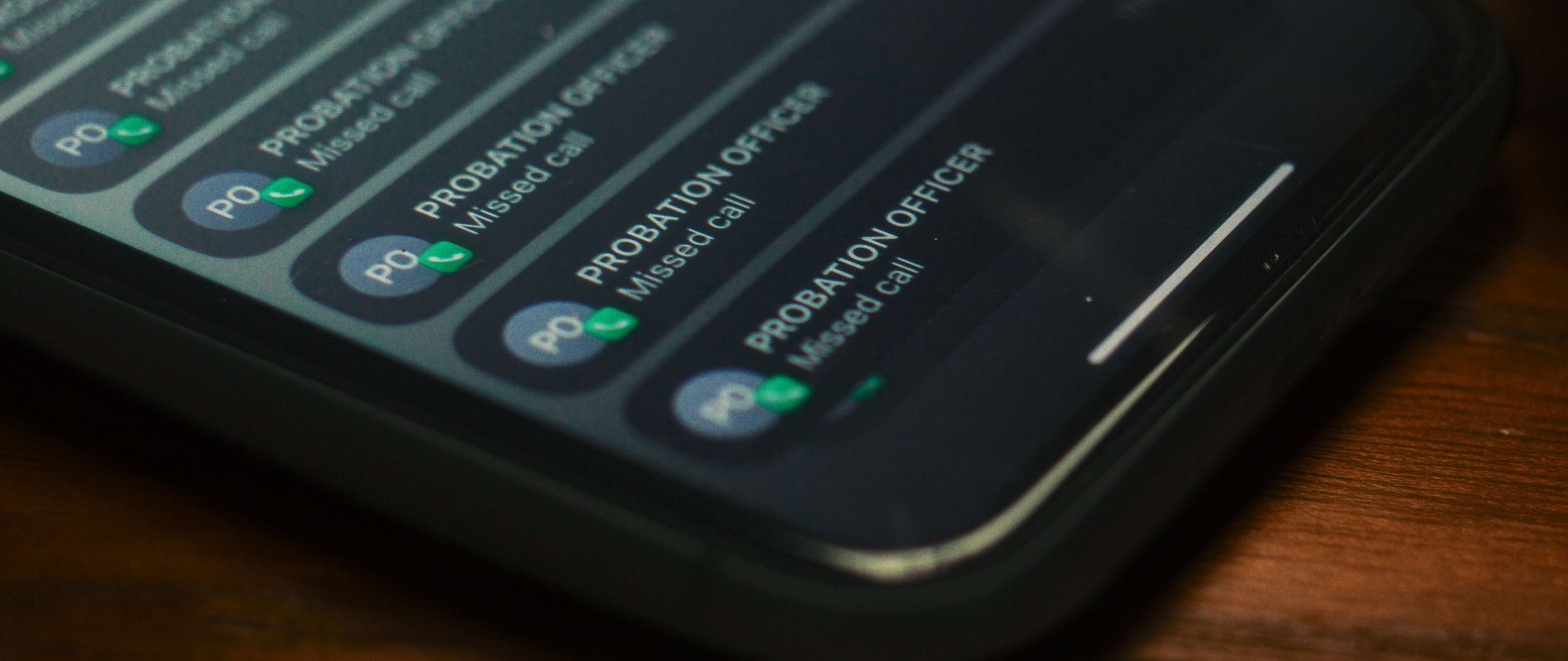 Close-up of a smartphone screen displaying multiple missed calls labeled 'PROBATION OFFICER' with green call icons.