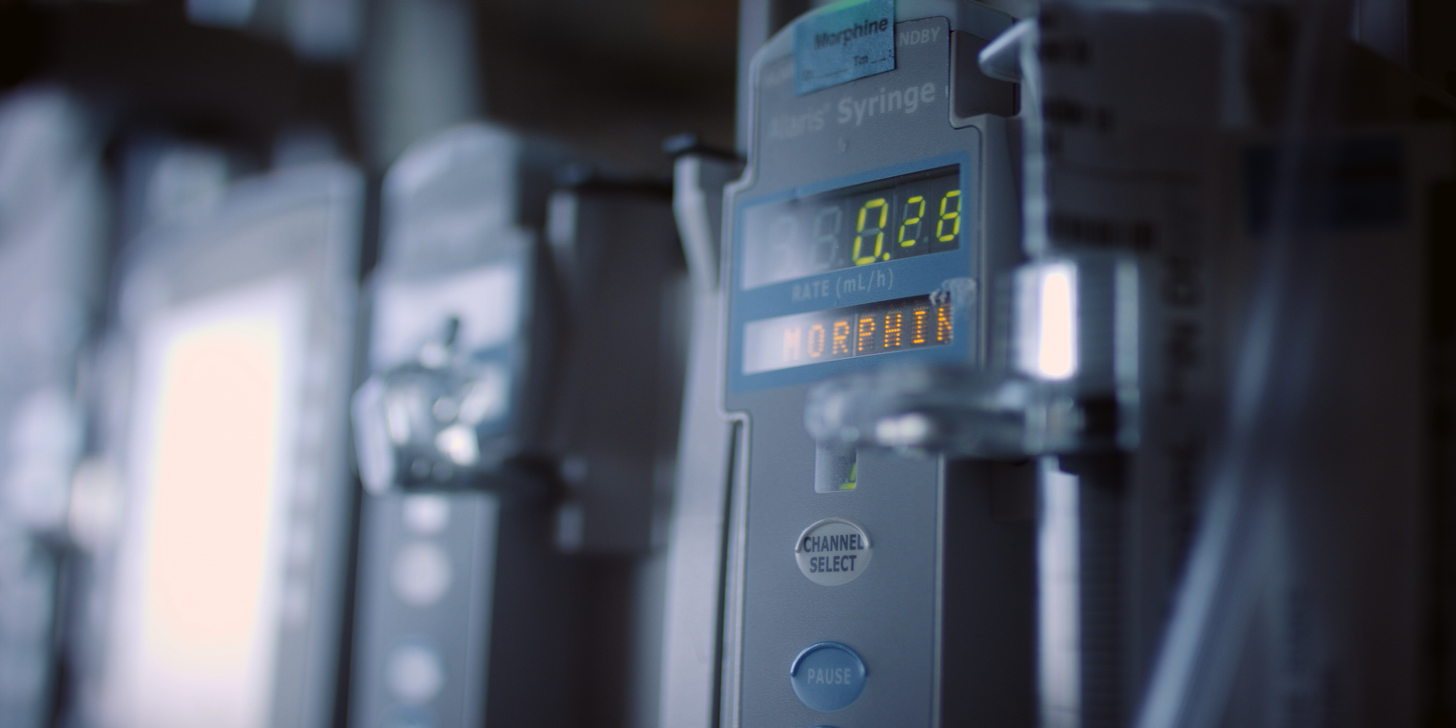 Close-up of an infusion pump displaying '0.28' mL/h and the word 'MORPHIN' in orange LED lights.