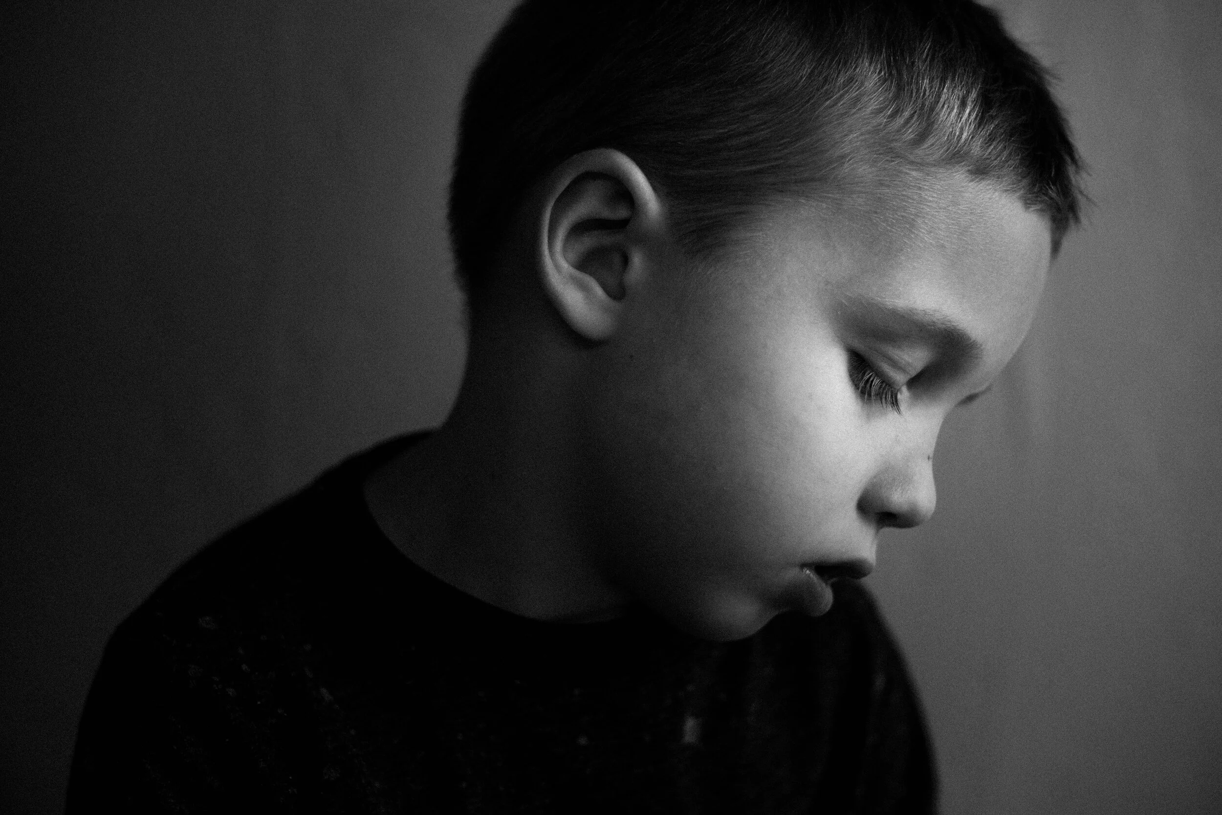 Side profile of a young person with closed eyes, short hair, and smooth skin in black-and-white.