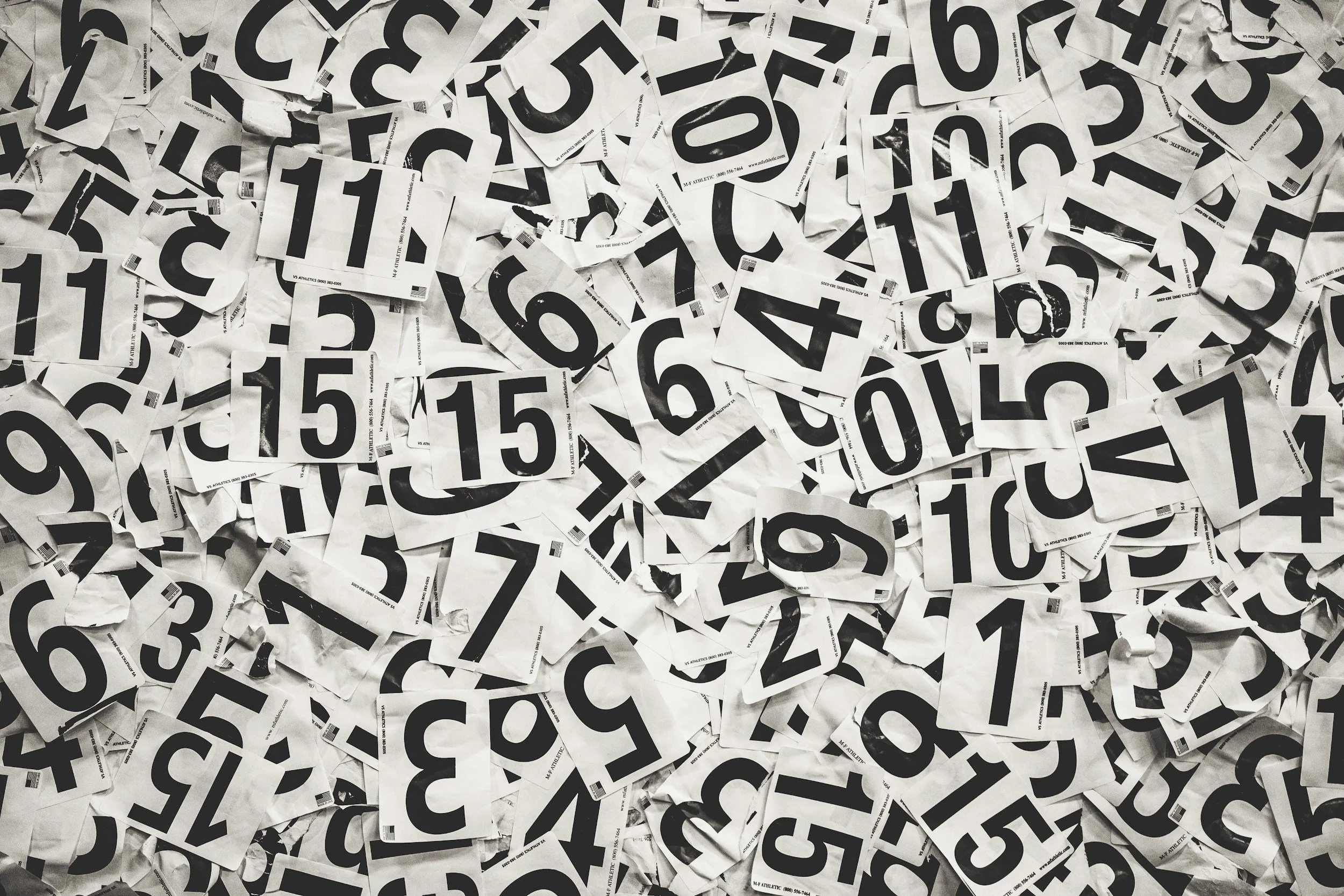 A pile of crumpled pieces of paper with large black numbers and barcodes on them.