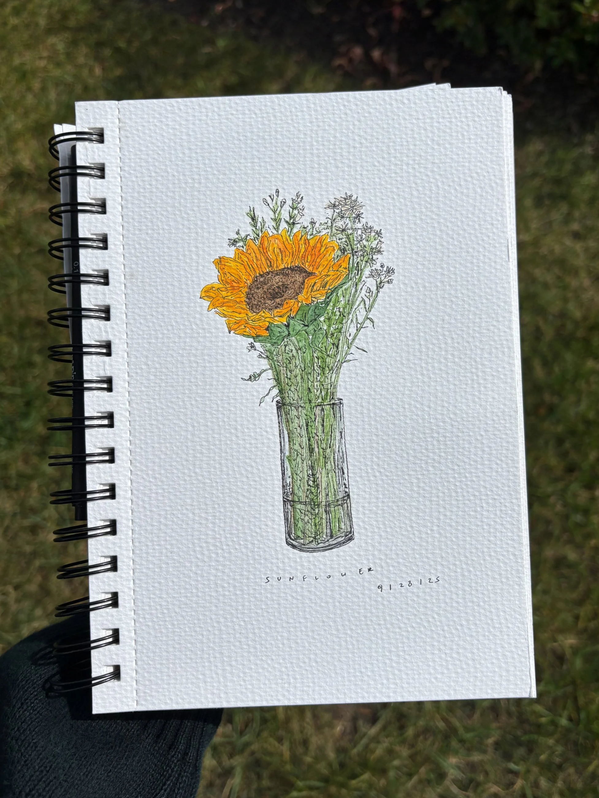 A drawing of a sunflower in a glass vase with small flowers around it, labeled 'Sunflower' at the bottom.
