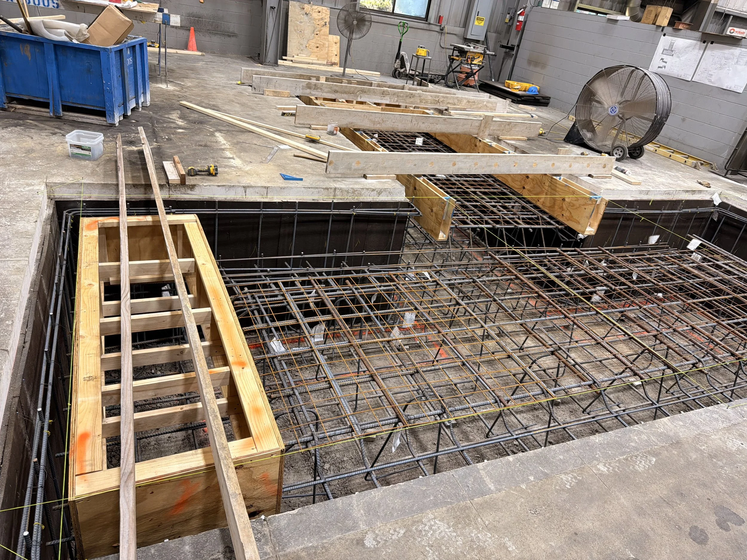 Construction site with wooden framing, metal rebar, and tools for building a structure floor or foundation.
