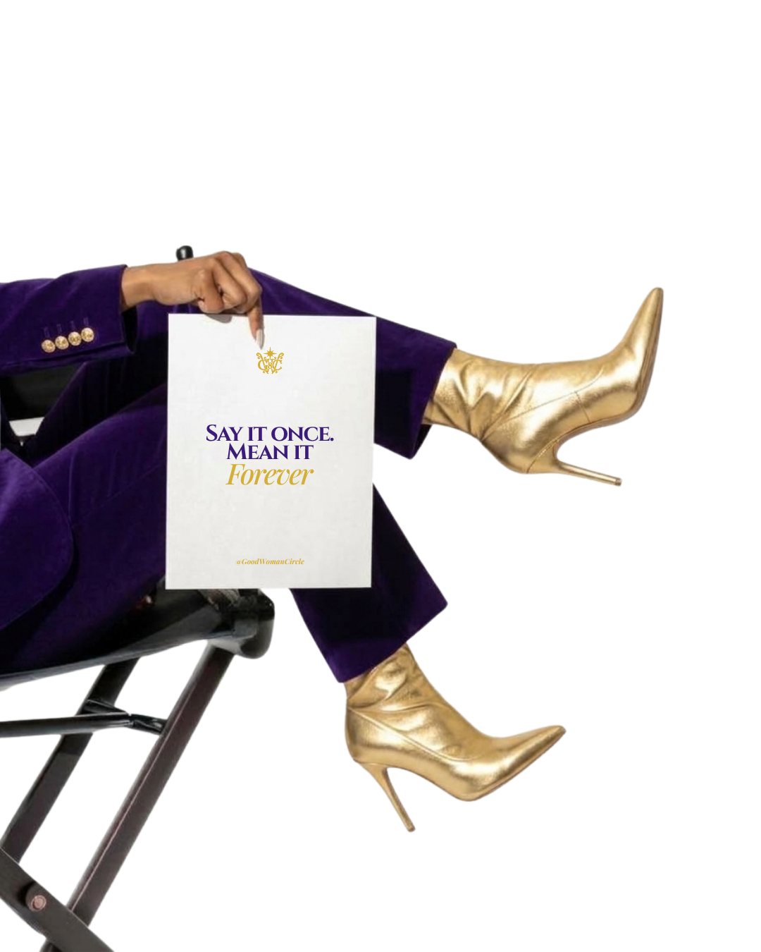 A woman in a purple suit and gold stiletto boots sits on a director's chair holding a card that reads Say it once. Mean it. Forever