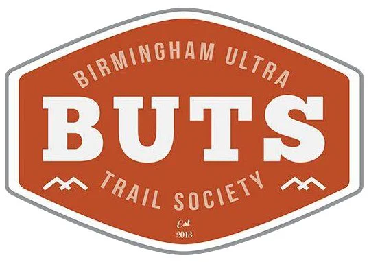 Logo for Birmingham Ultra Buts Trail Society, established in 2013, featuring a white and gray outline on an orange background with text.