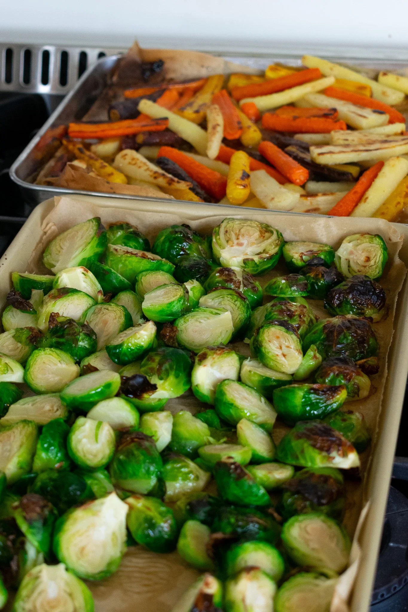 Roasted brussels sprouts and mixed roasted vegetables on baking sheets.