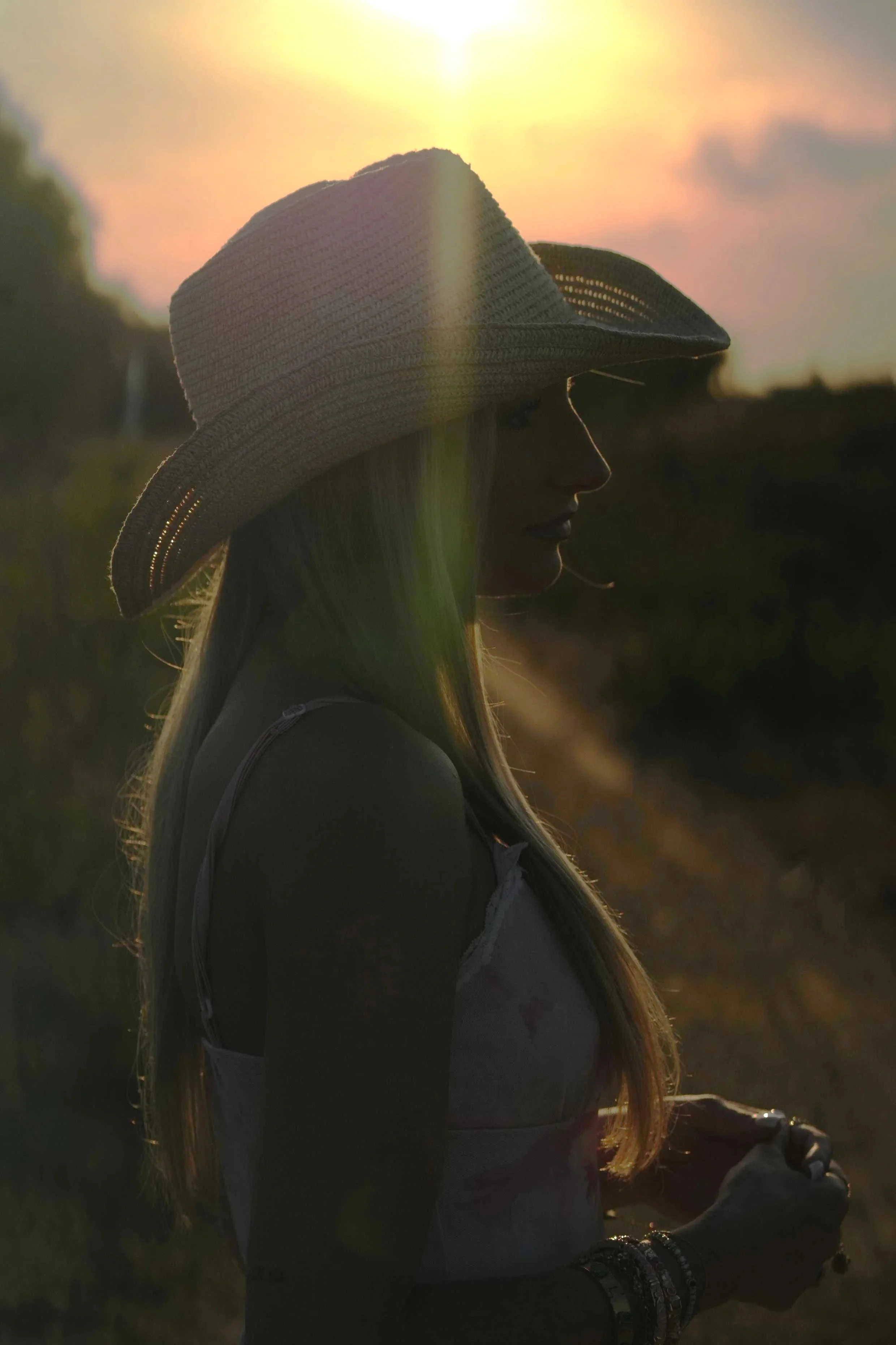Silhouette d'une femme portant un chapeau en paille, vue de profil, au coucher du soleil