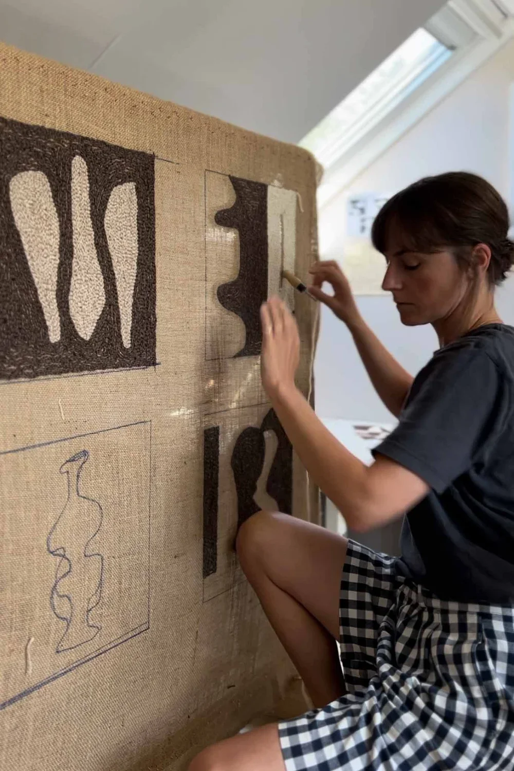 A woman working on an art piece involving cut-out shapes on a large canvas.