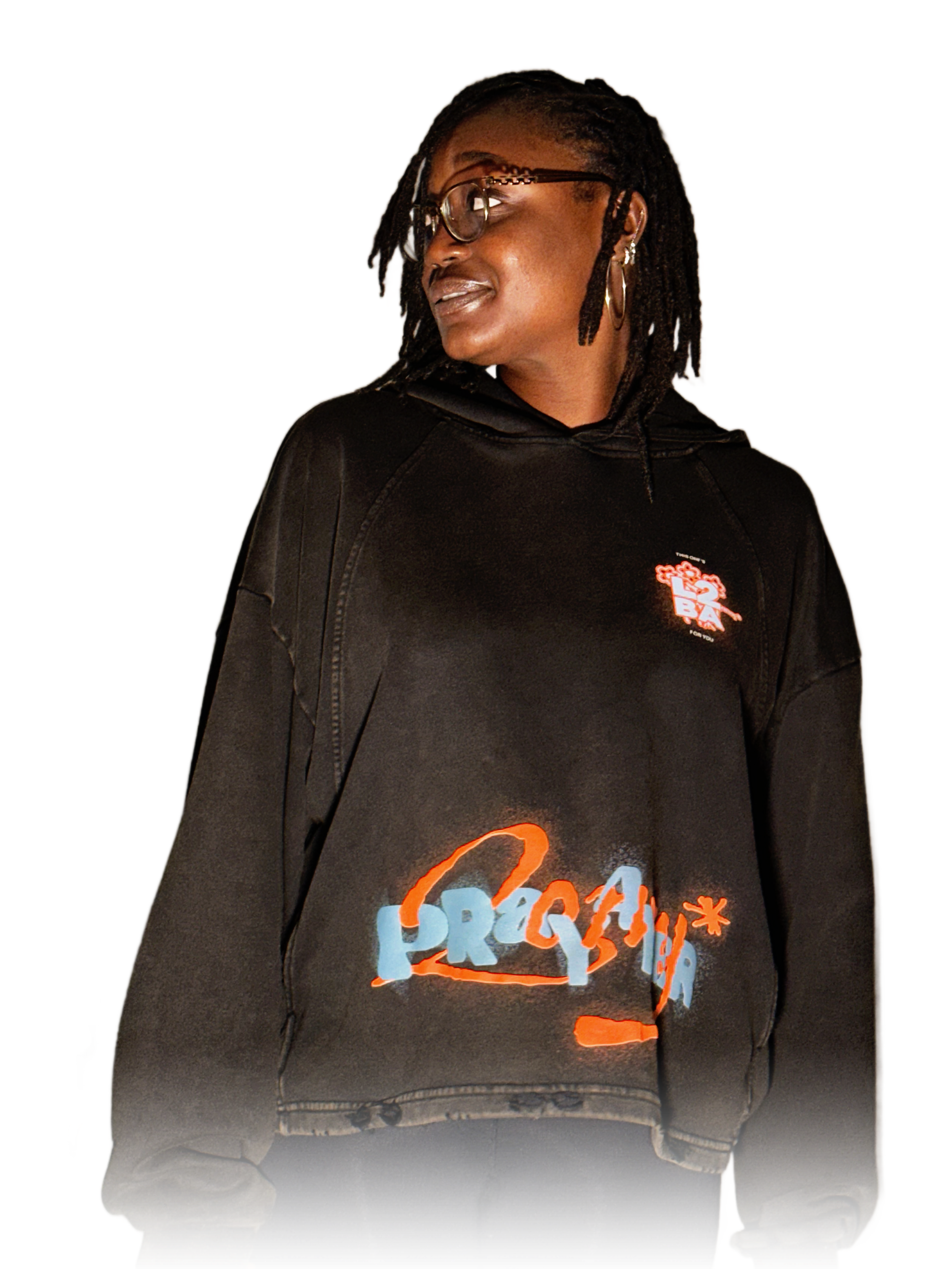 darkskin female model wearing black Pray 4 Her Hoodie by the HARMMONEY brand
